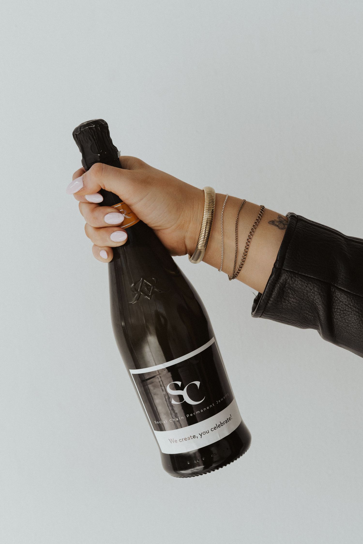 Hands holding a dark wine bottle against white background.