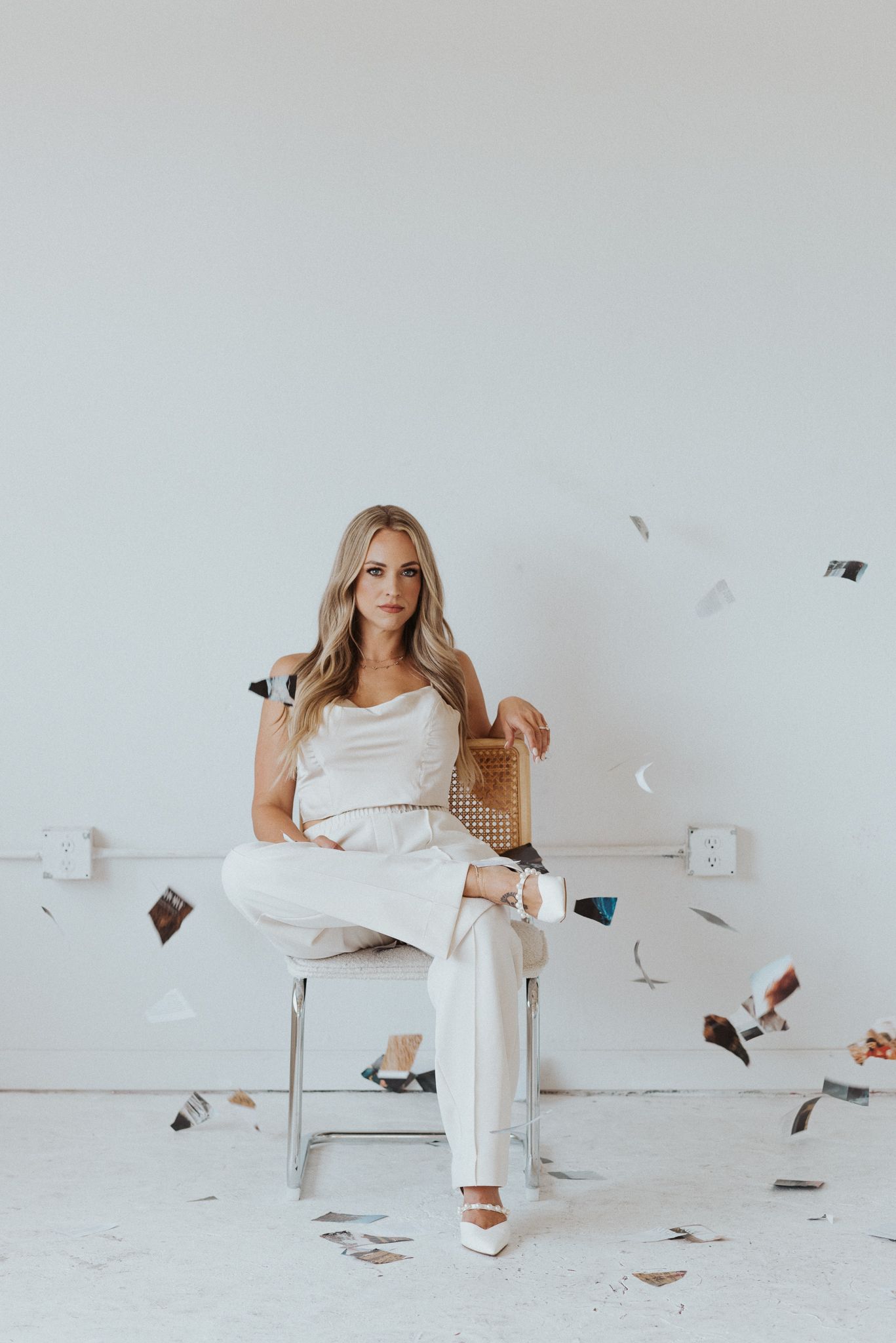 Figure in white lounging on couch with flying papers creating artistic motion effect.