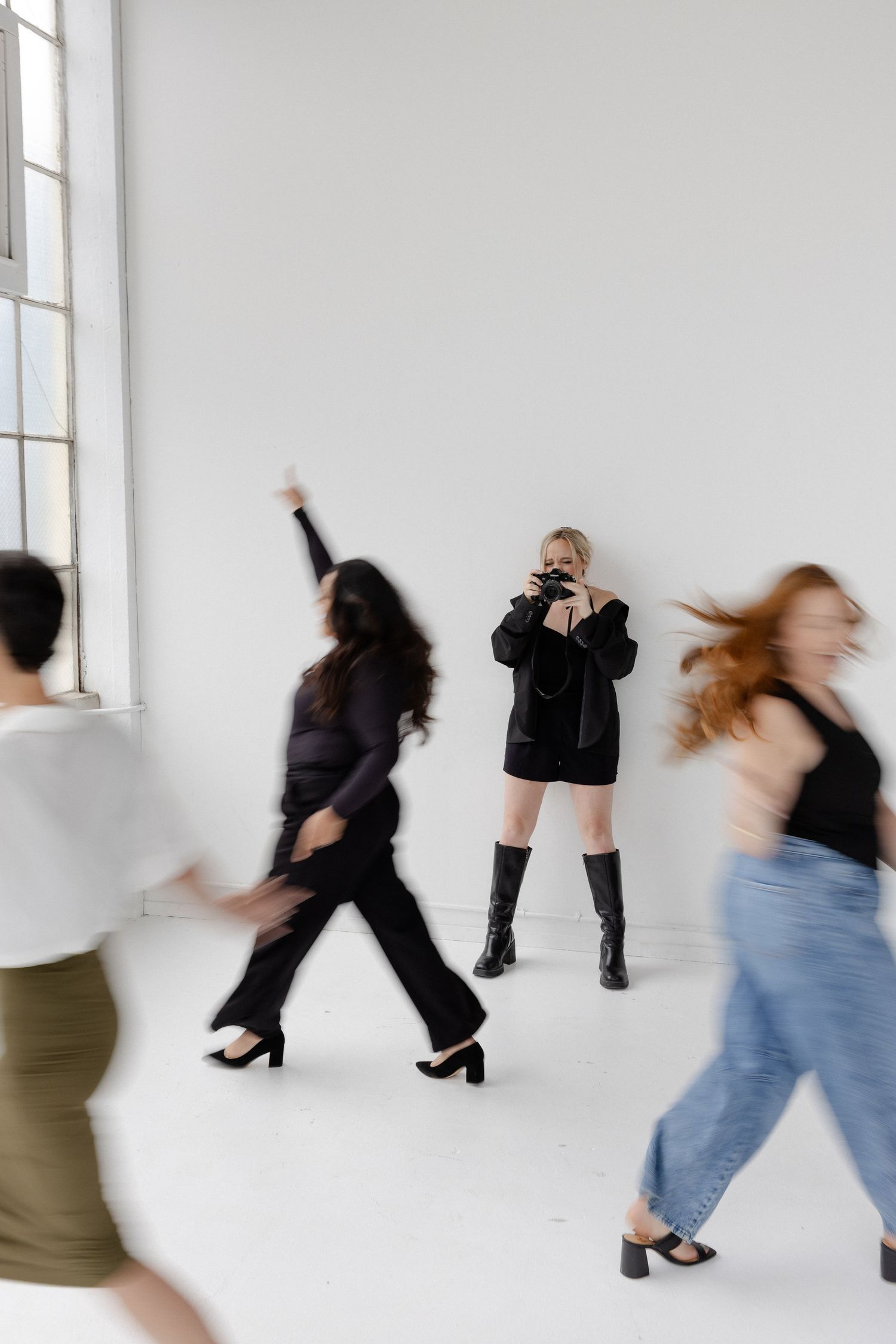 Motion blur sequence of people dancing and moving in white studio space.