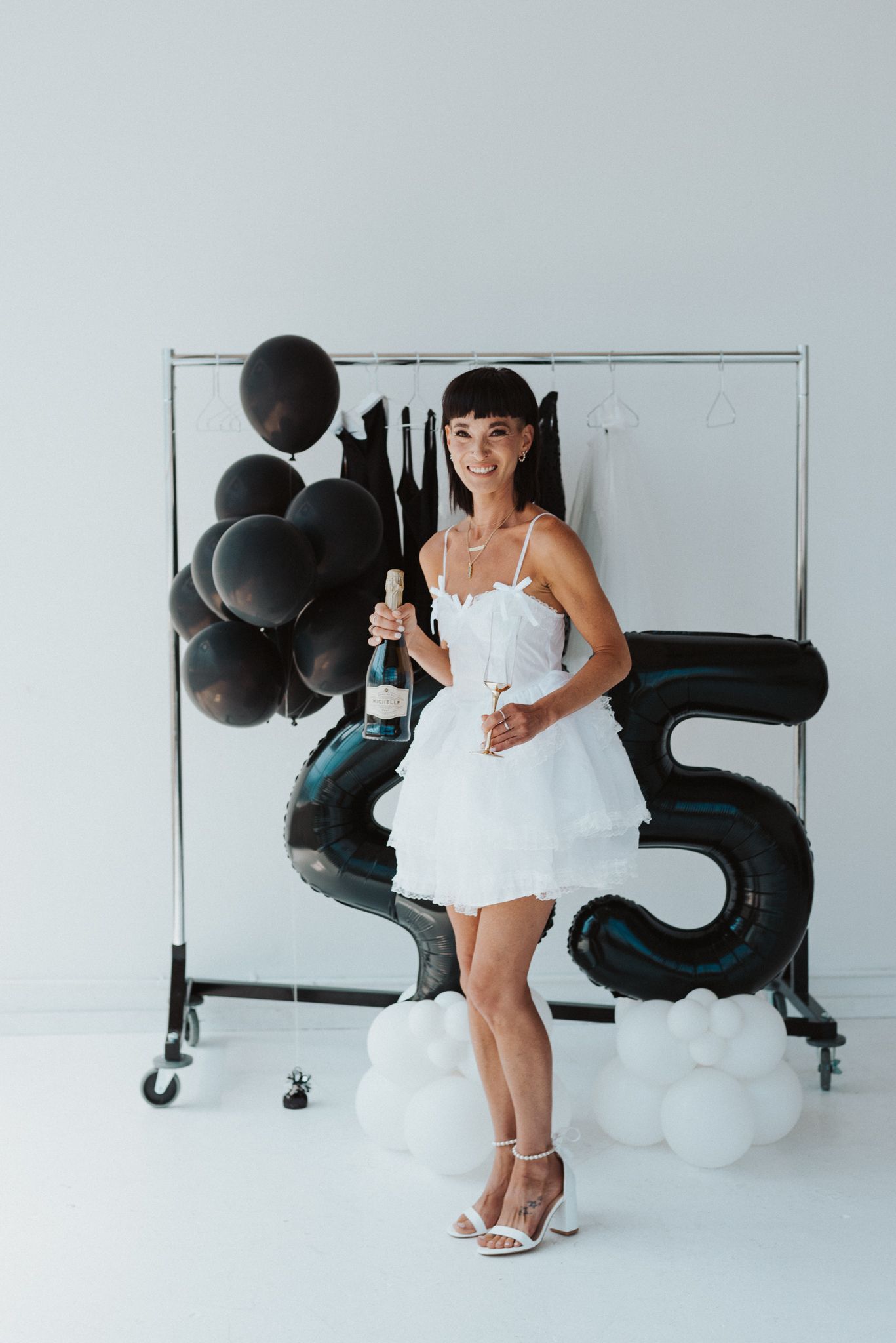 Studio photoshoot setup with black balloons and white decorative elements against light background.