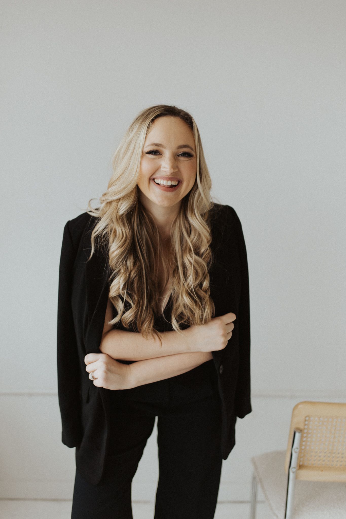 Casual portrait session showing joyful expressions in black attire against white wall.
