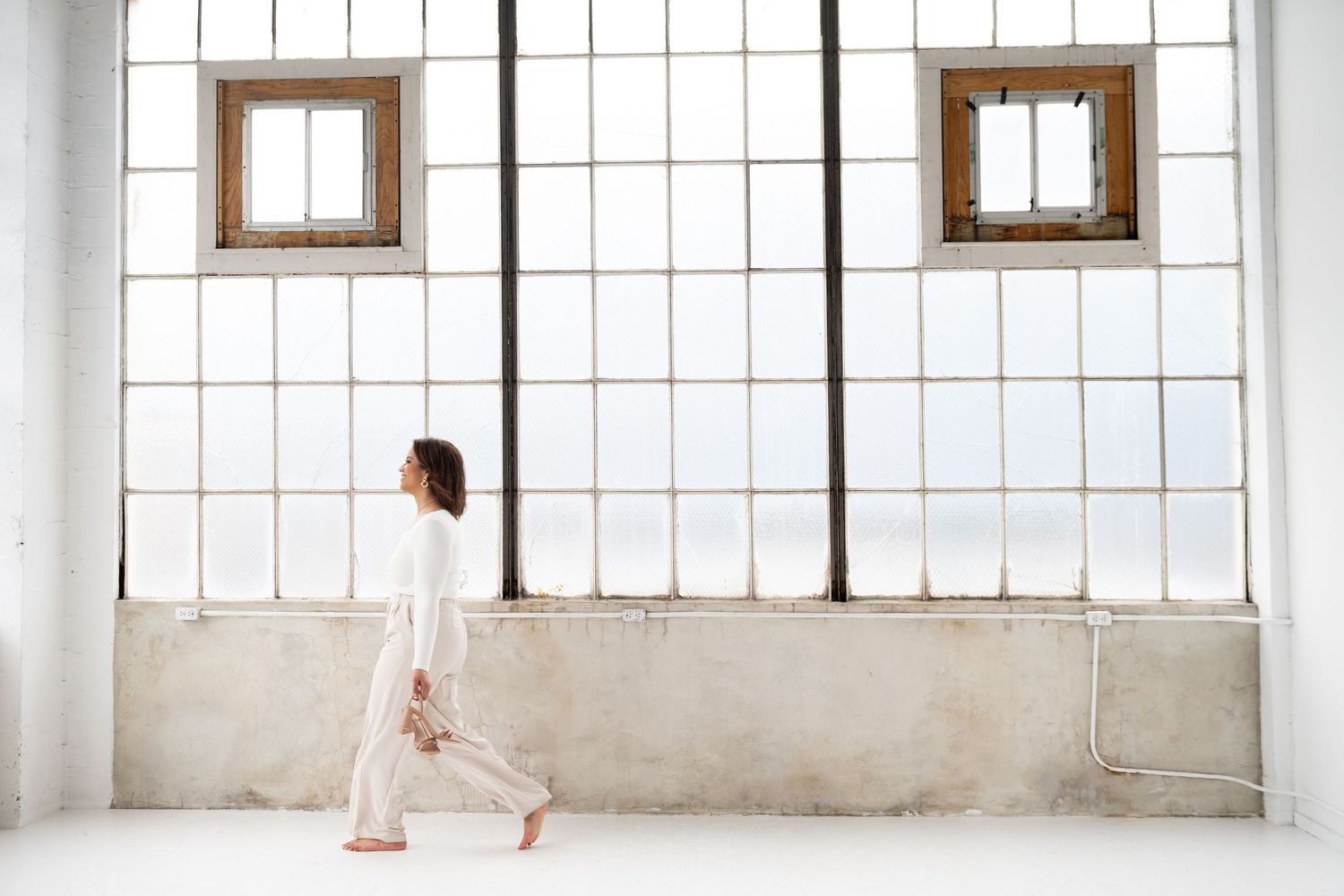 Wide panoramic view of bright studio space with large industrial windows and natural light.