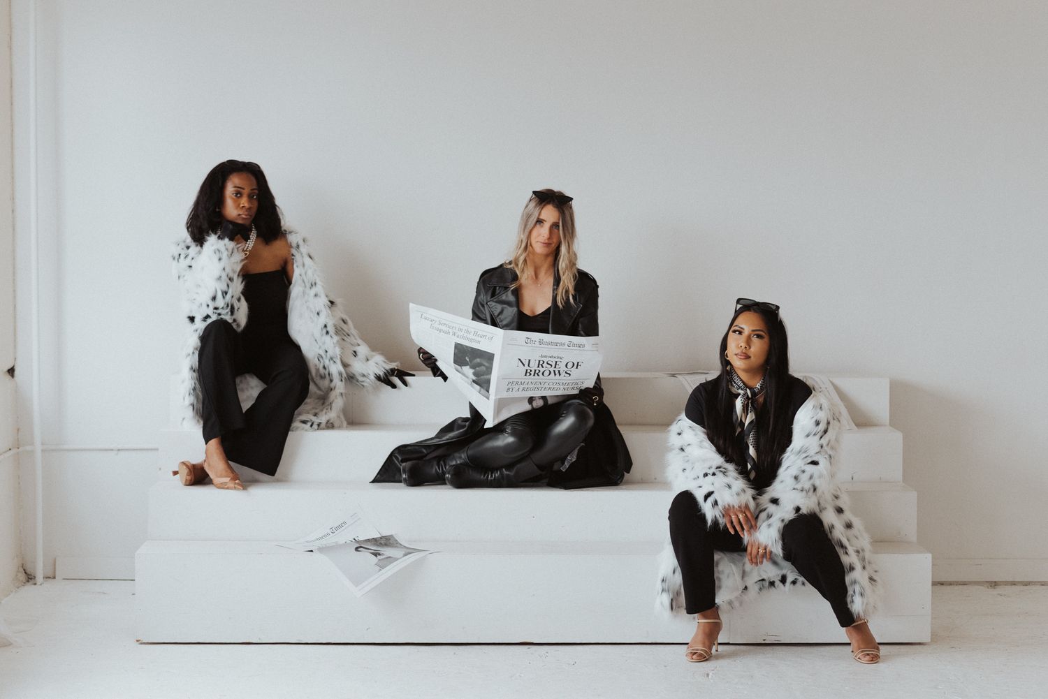 Creative studio session with people in casual wear sitting against white wall.