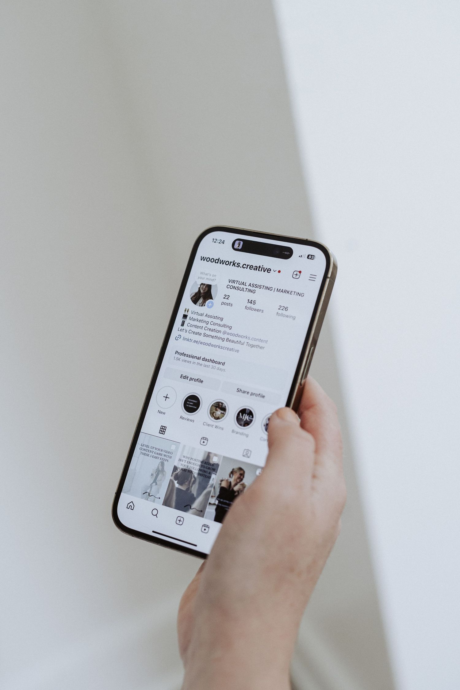 Hand holding smartphone displaying social media profile interface against white background.