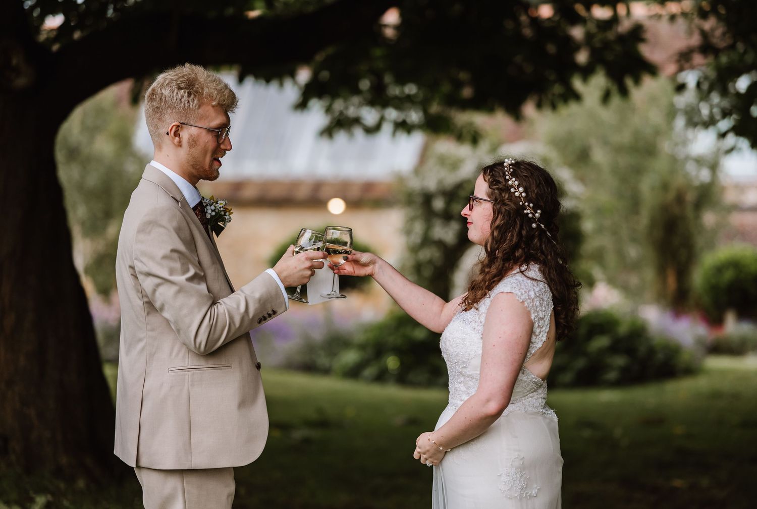 Bride and groom sharing a candle lighting ceremony outdoors in a lush garden on their wedding day at Symmondbury Tithe Barn, Bridport
