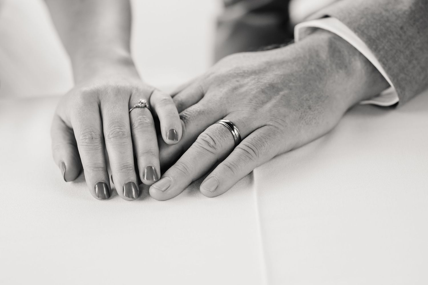 Close-up view of hands with engagement ring showing detail of diamond solitaire on white background. Relaxed Somerset Wedding photographer
