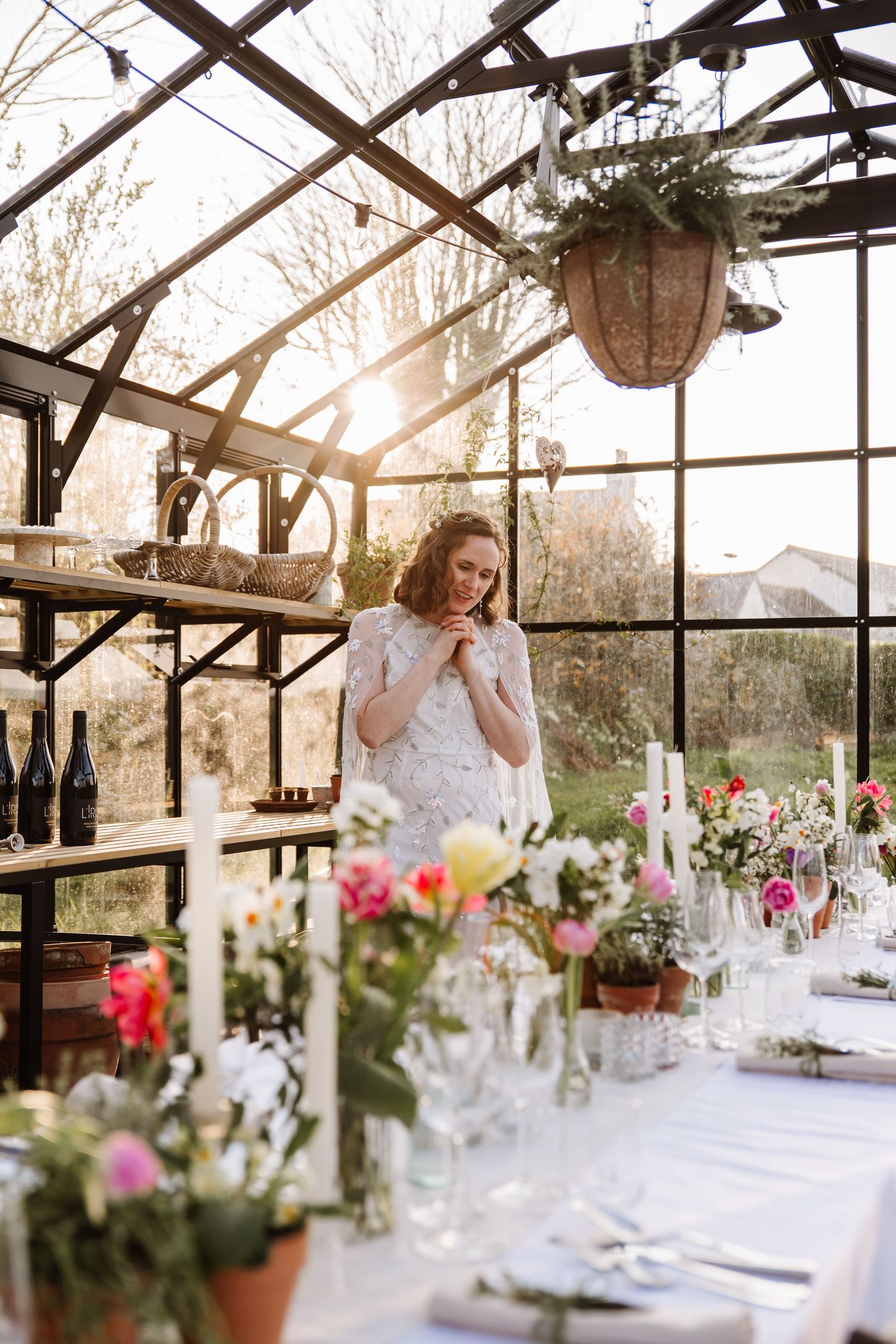 Bride and groom admire a floral-decorated wedding reception table inside a sunlit glass greenhouse venue. The Cornish Place wedding venue