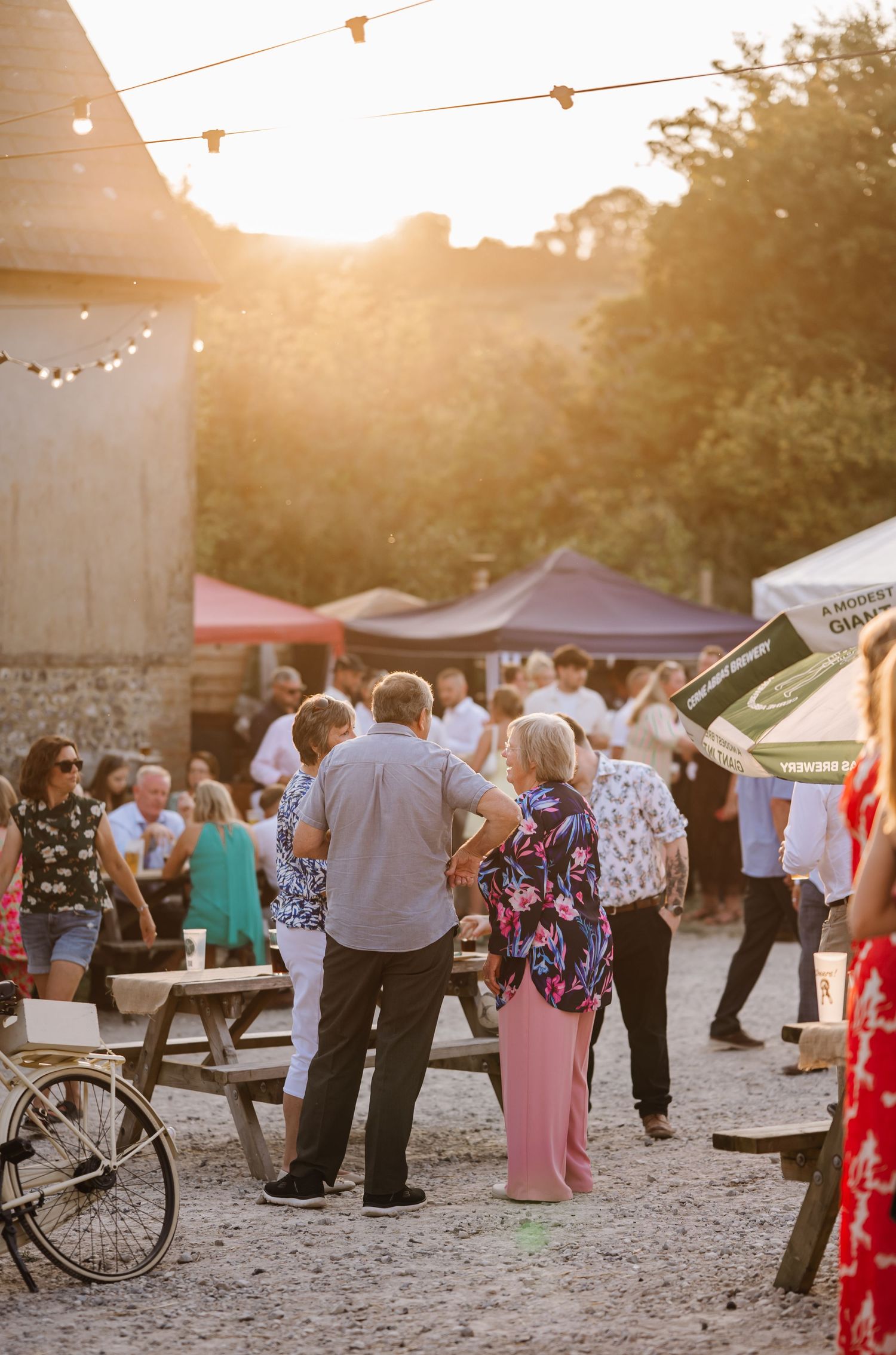 Guests enjoy golden hour at Dorset Festival barn wedding at Cerne Abbas Brewery. Candid photos from a relaxed Dorset wedding photographer