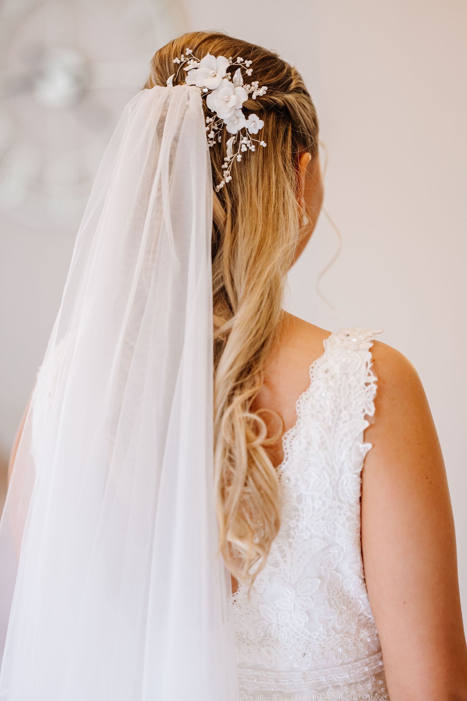 Bride with half-up hairstyle, floral hair comb, and flowing white veil, wearing a lace wedding dress at St Audries