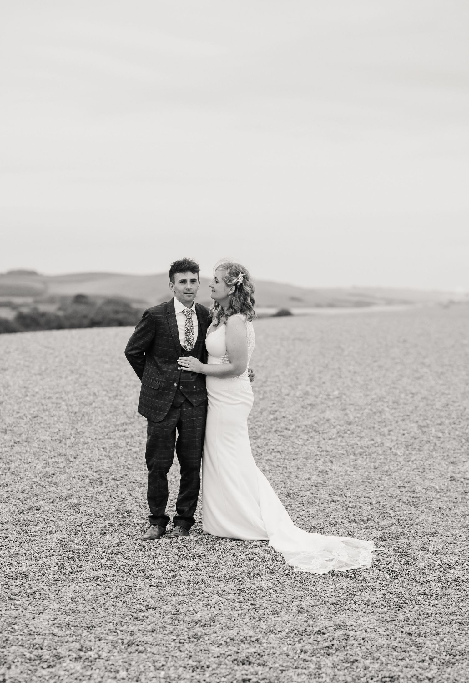 Bride and groom on Chesil Beach following their wedding at Abbotsbury Subtropical Gardens. Candid wedding photographer based in Weymouth