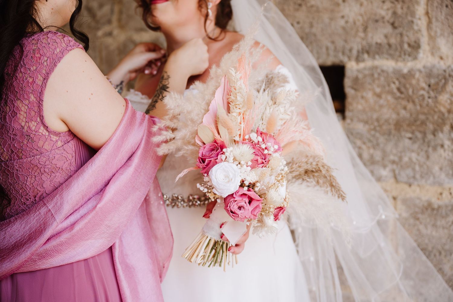 Bride holding a pink and white bouquet with pampas grass, assisted by bridesmaid in purple dress after Westgate, Southampton
