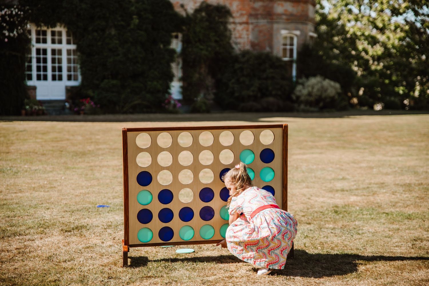 Weymouth wedding photography girls plays connect four at Dorset wedding venue Clayesmore school. Wedding garden game hire from The Hire Barn