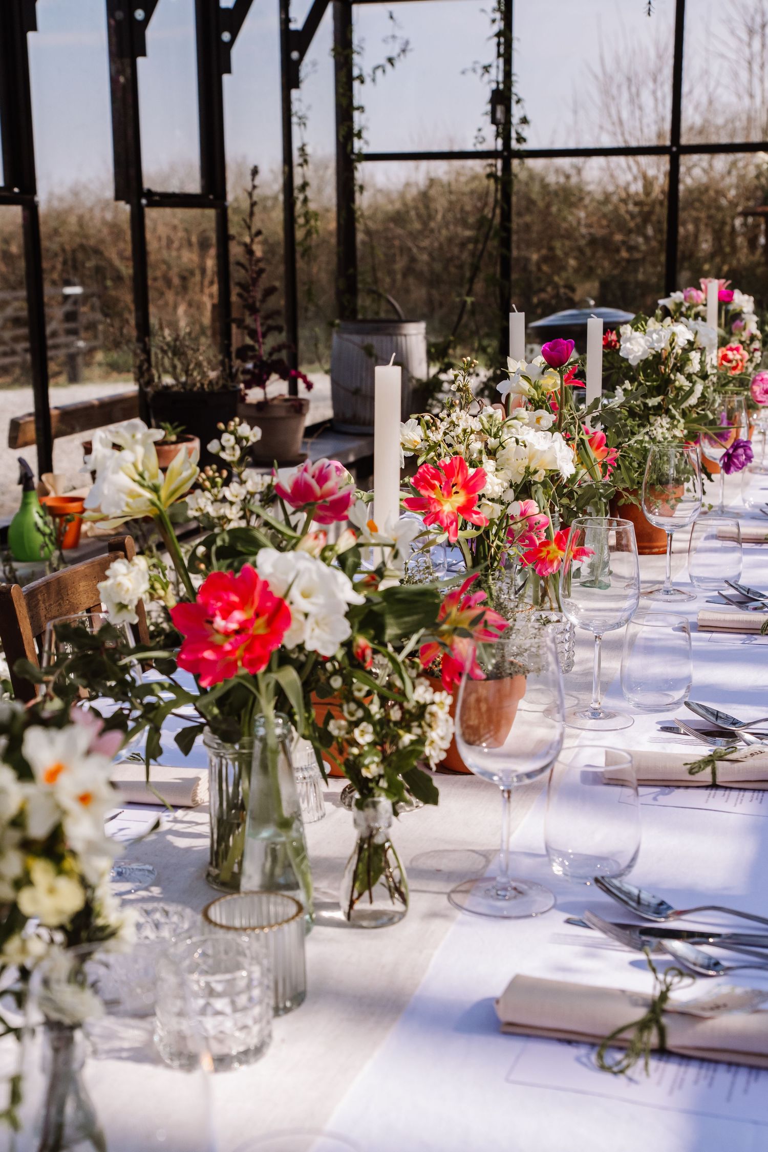 Floral-decorated reception table inside a sunlit glass greenhouse venue. The Cornish Place wedding venue. Unusual wedding venues, Cornwall