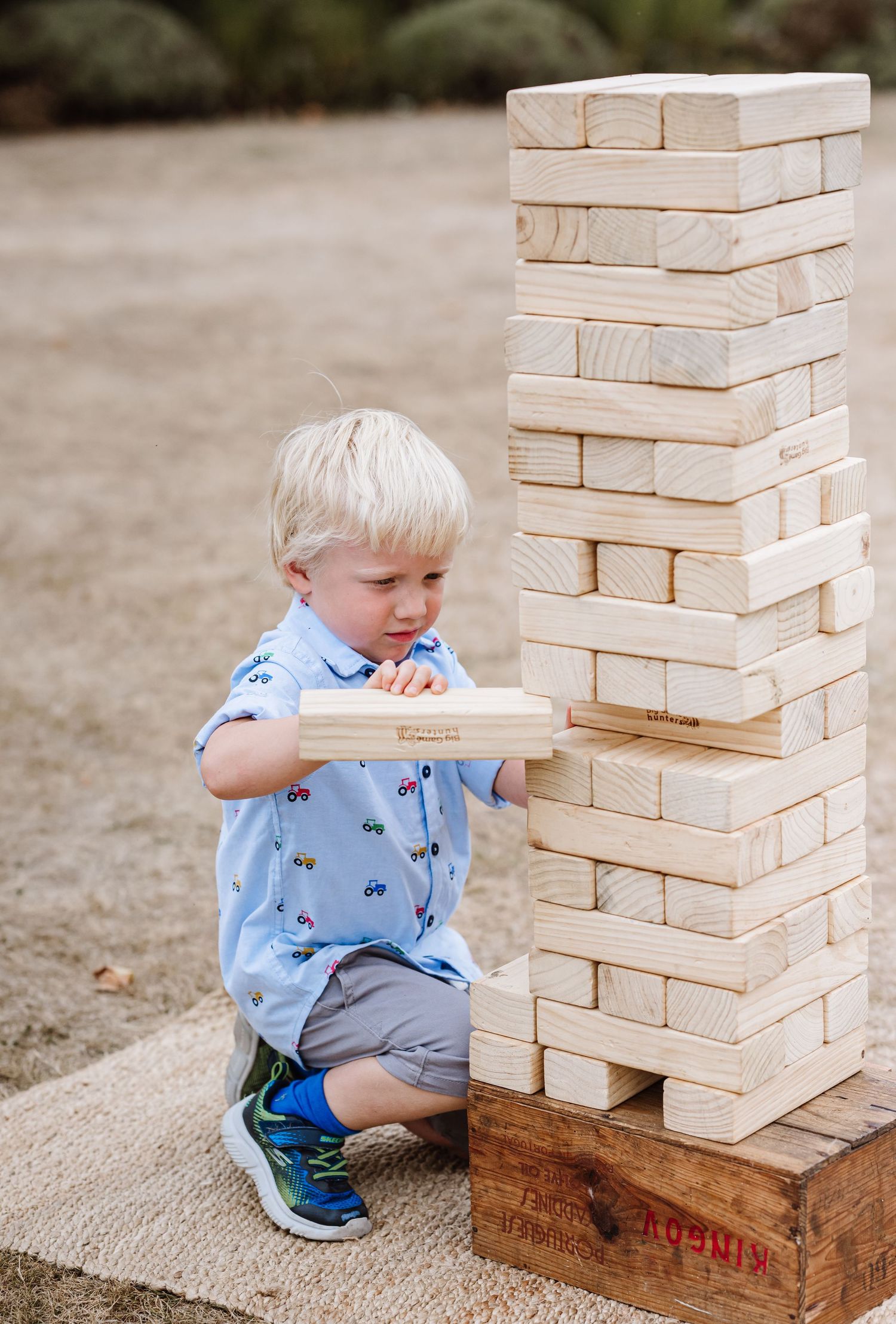 Weymouth wedding photography. Wedding garden game hire  Little boy in blue suit plays jenga at a wedding at Clayesmore School, Blandford.