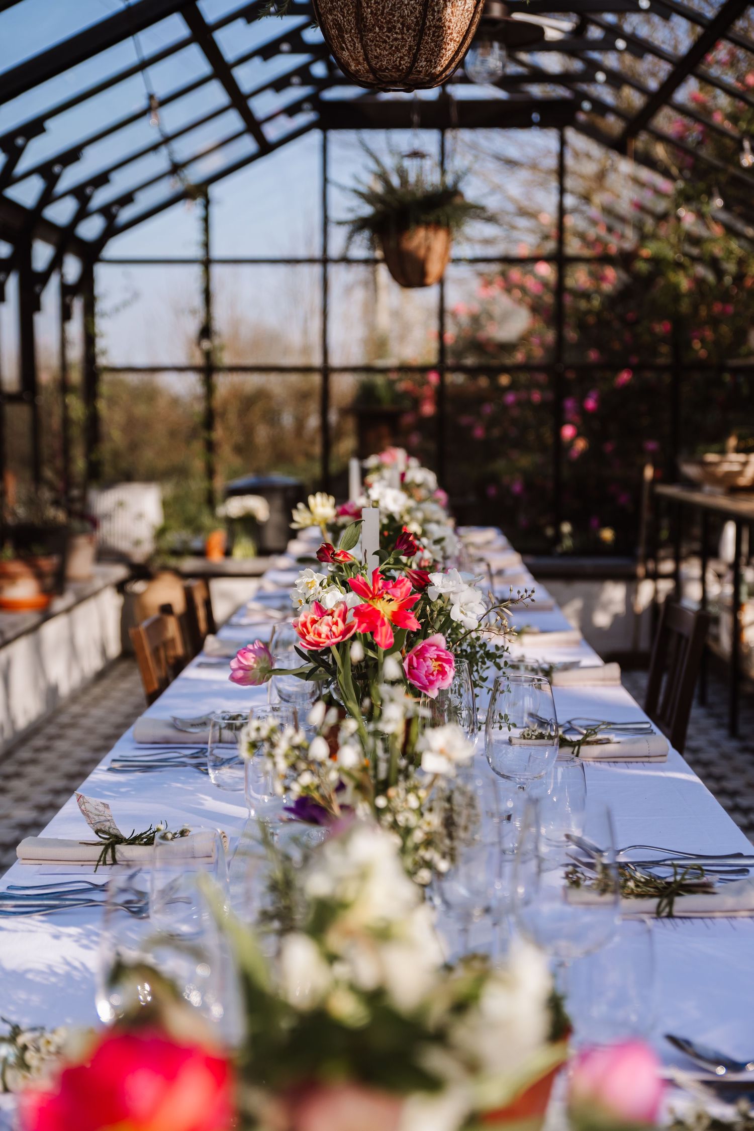 Floral-decorated reception table inside a sunlit glass greenhouse venue. The Cornish Place wedding venue. Unusual wedding venues, Cornwall