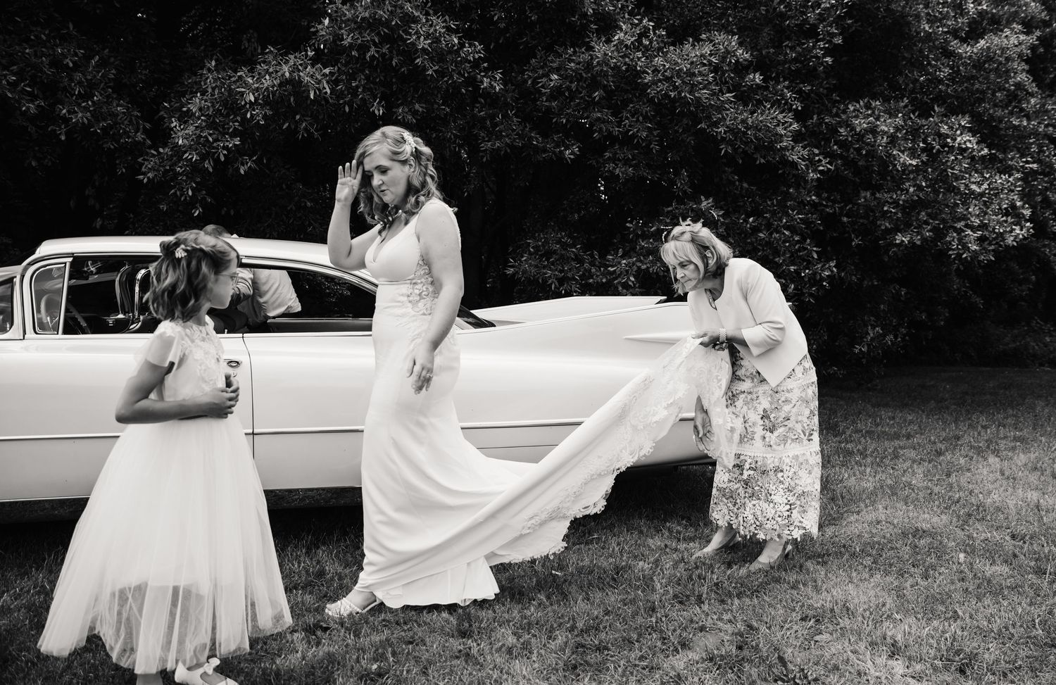 Bride gets out of Cadillac at Abbotsbury Subtropical Garden wedding. Outdoor wedding venue in Dorset, Candid Weymouth wedding photographer