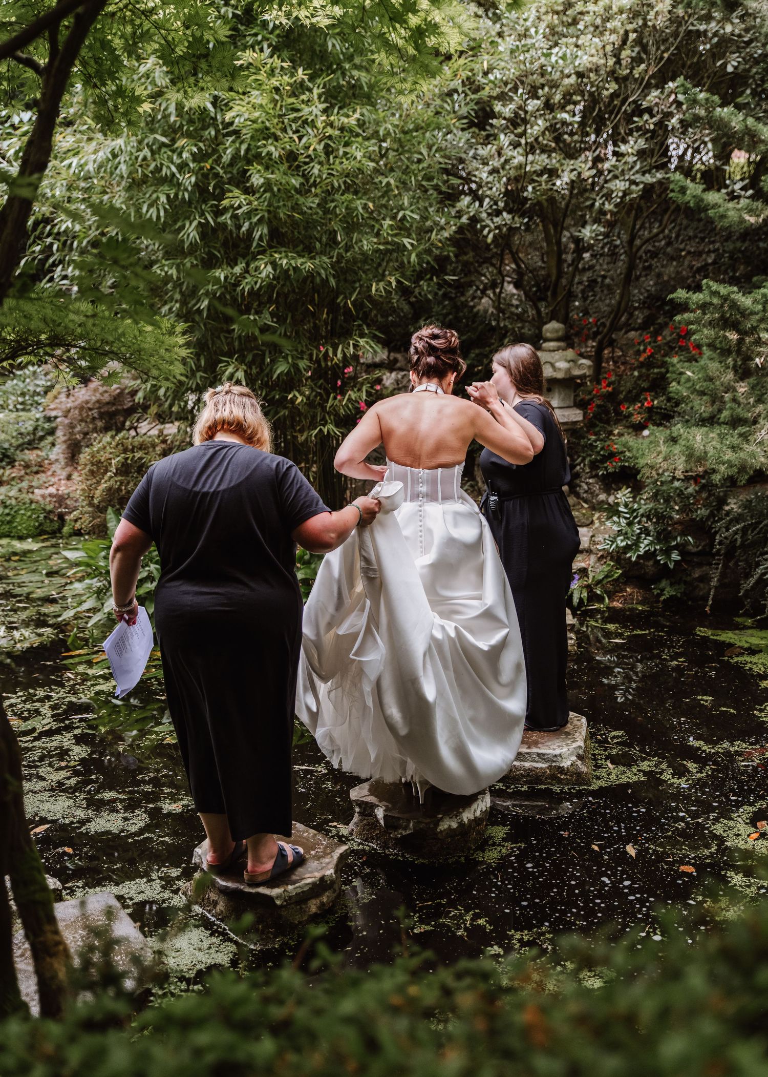 Bride crosses stepping stones at Italian Villa, Compton Acres Poole from a Dorset candid wedding photographer