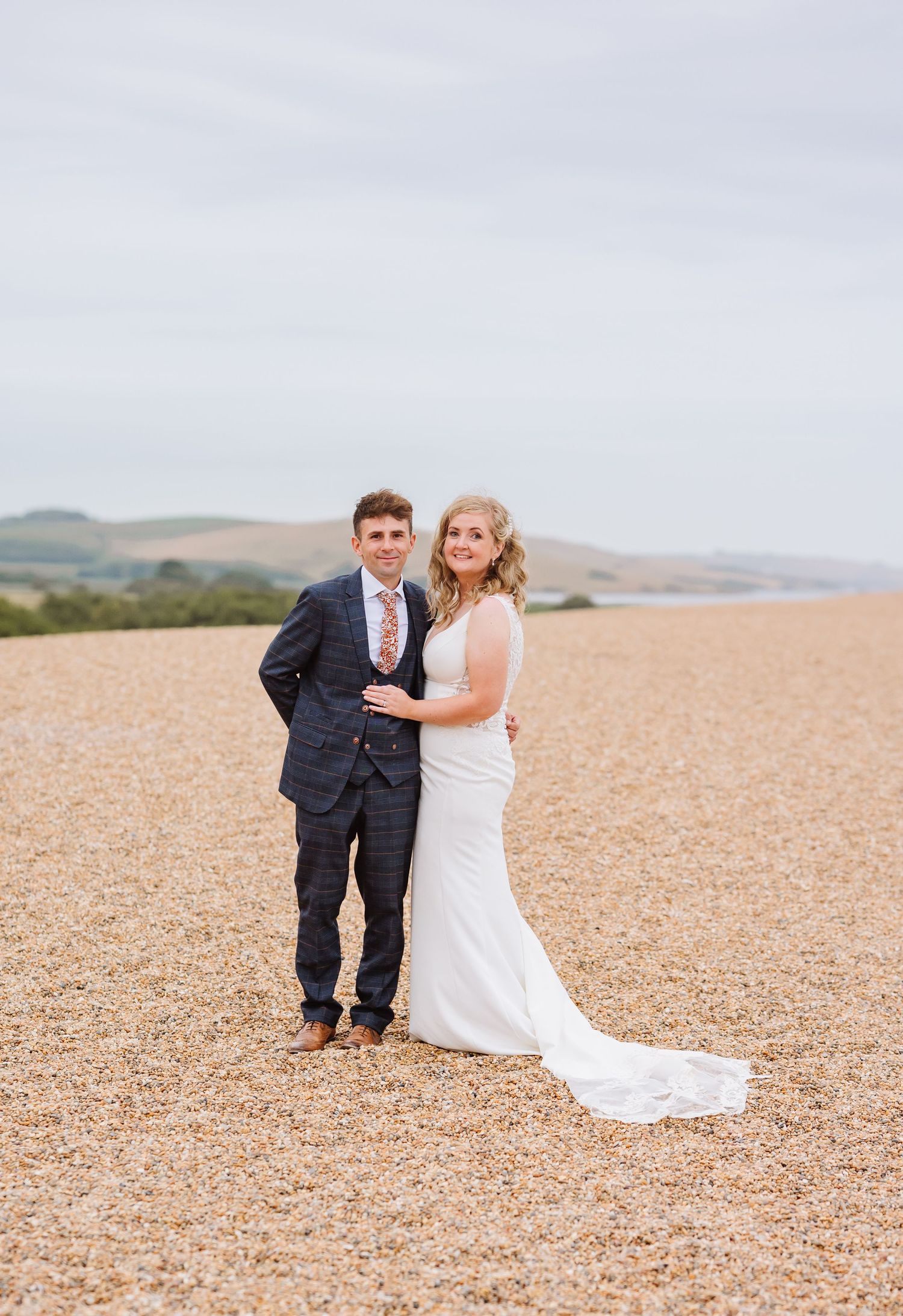 Bride and groom on Chesil Beach following their wedding at Abbotsbury Subtropical Gardens. Candid wedding photographer based in Weymouth