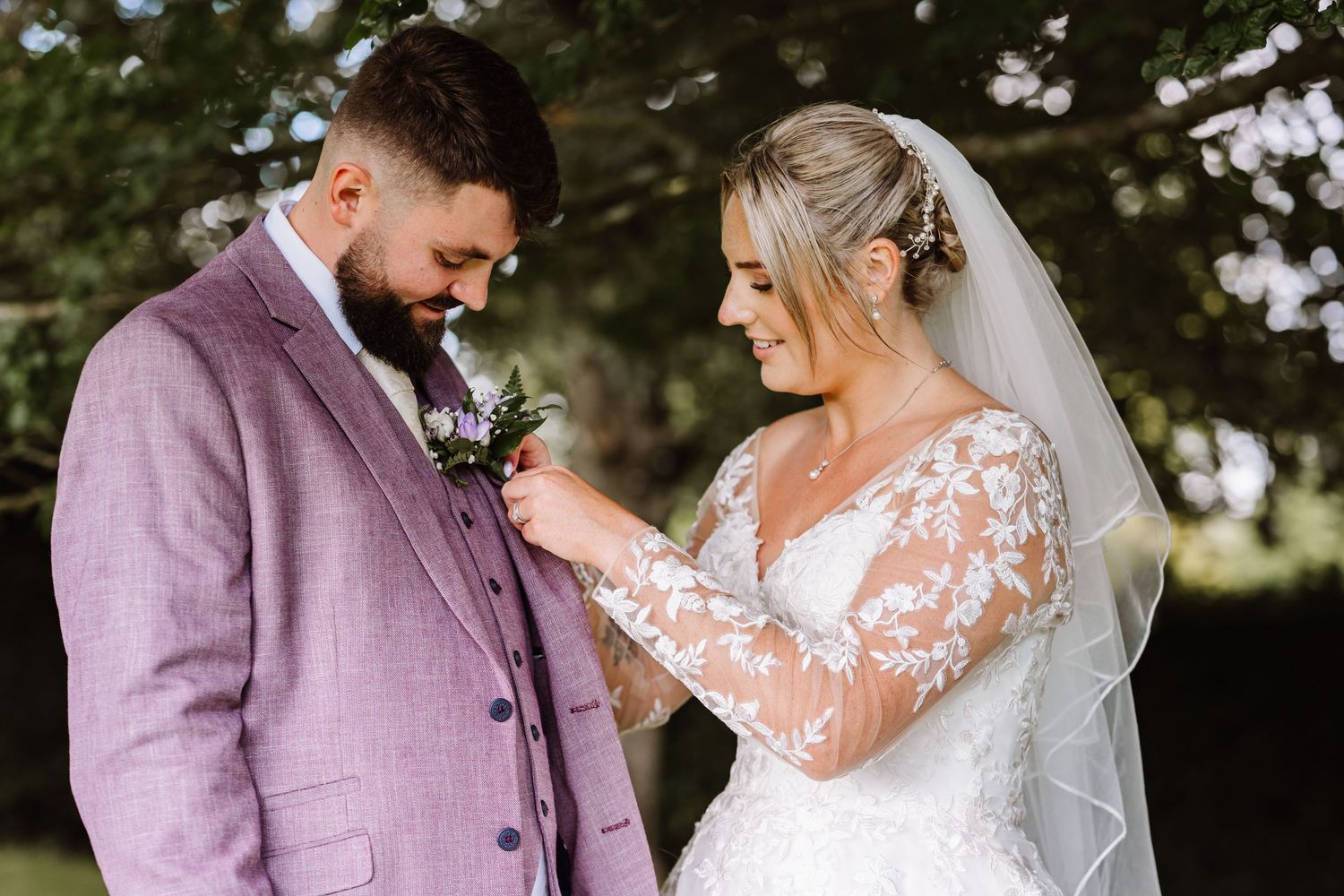 A romantic wedding couple shares intimate moments in an outdoor garden setting wearing lavender and white attire at Kingston Maurward Estate