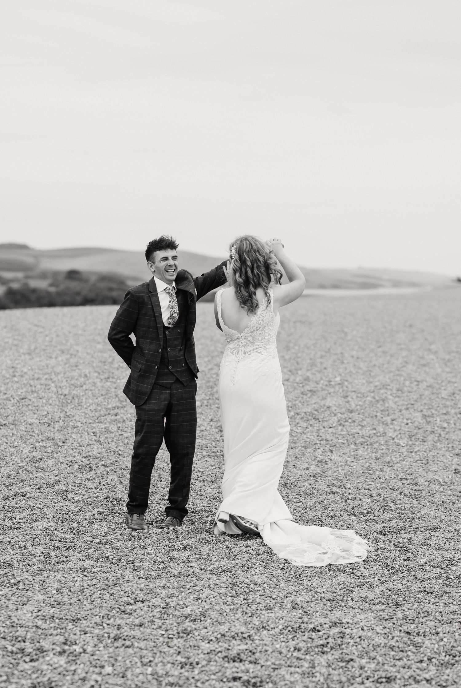 Bride and groom on Chesil Beach following their wedding at Abbotsbury Subtropical Gardens. Candid wedding photographer based in Weymouth