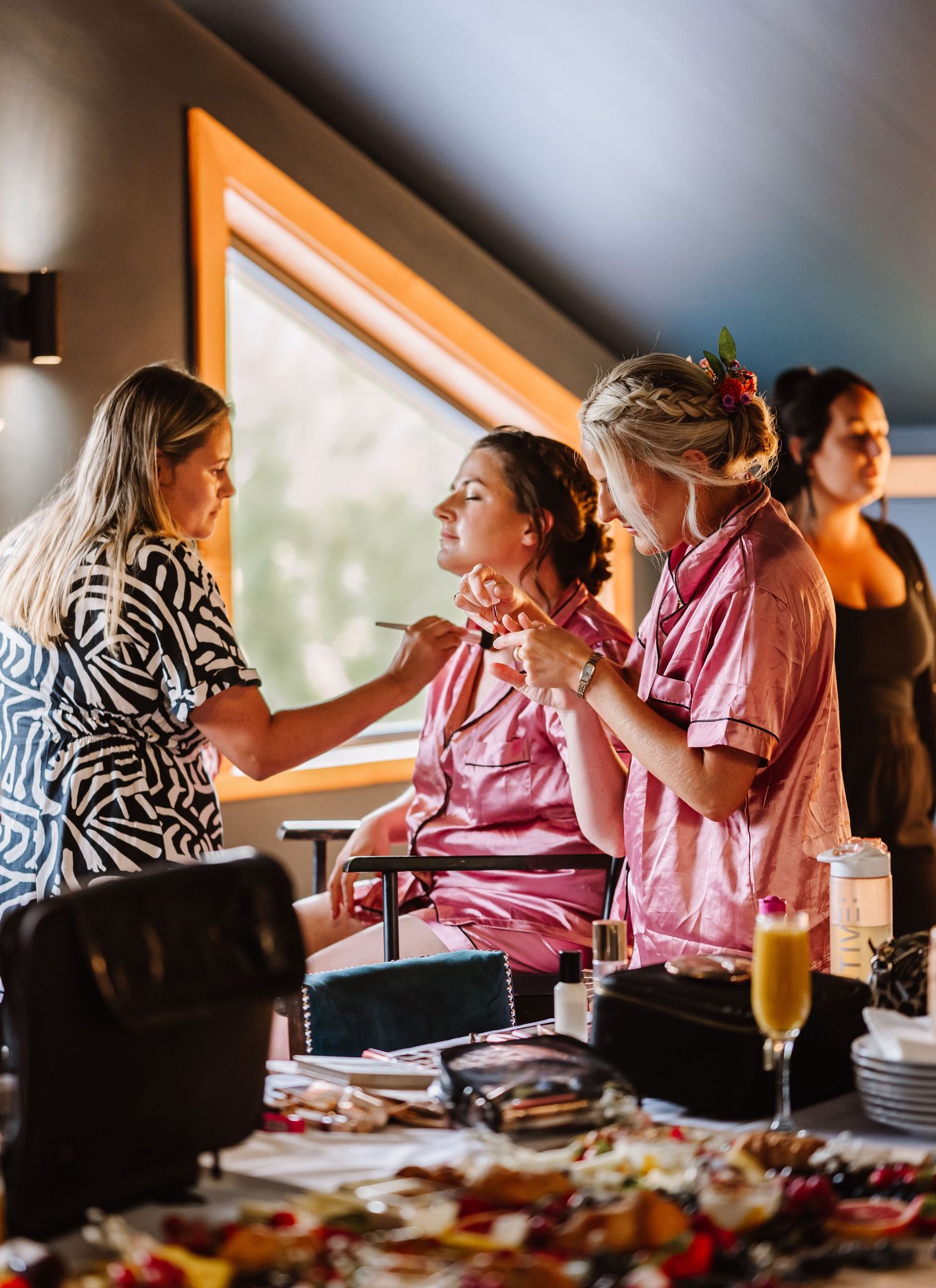 People getting ready in a room with makeup and mimosas during wedding preparations at the Waterside Barn and Mill lakeside wedding venue,