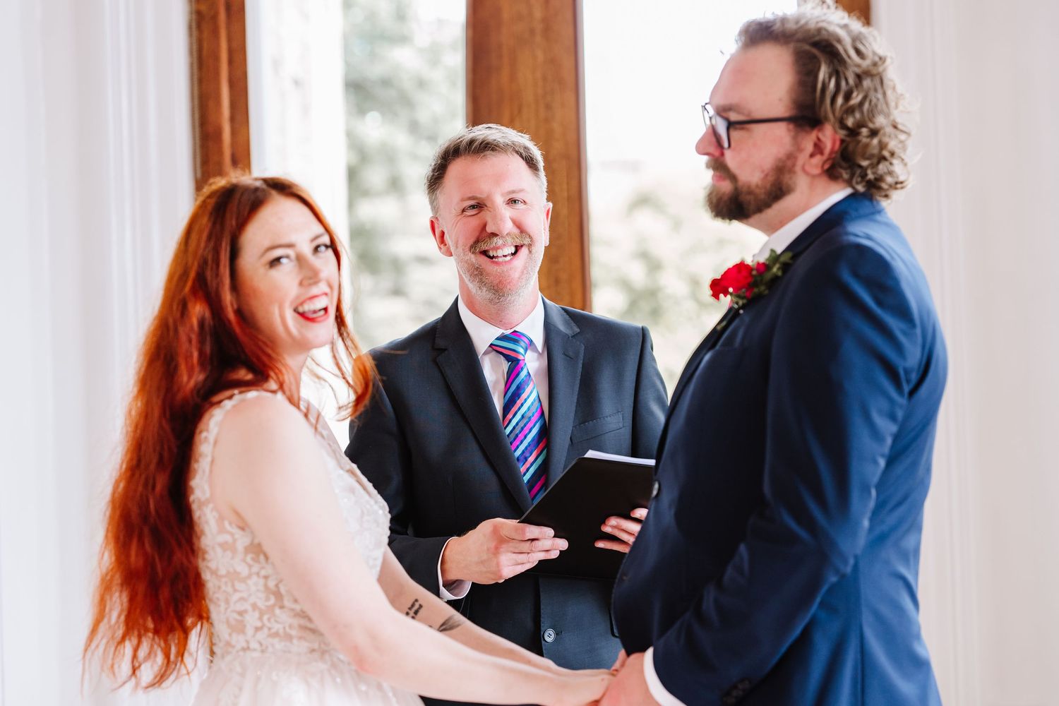 Bride with red hair and blush dress laughes during ceremony at Iwerne House, Blandford wedding venue Dorset. Candid wedding photographer