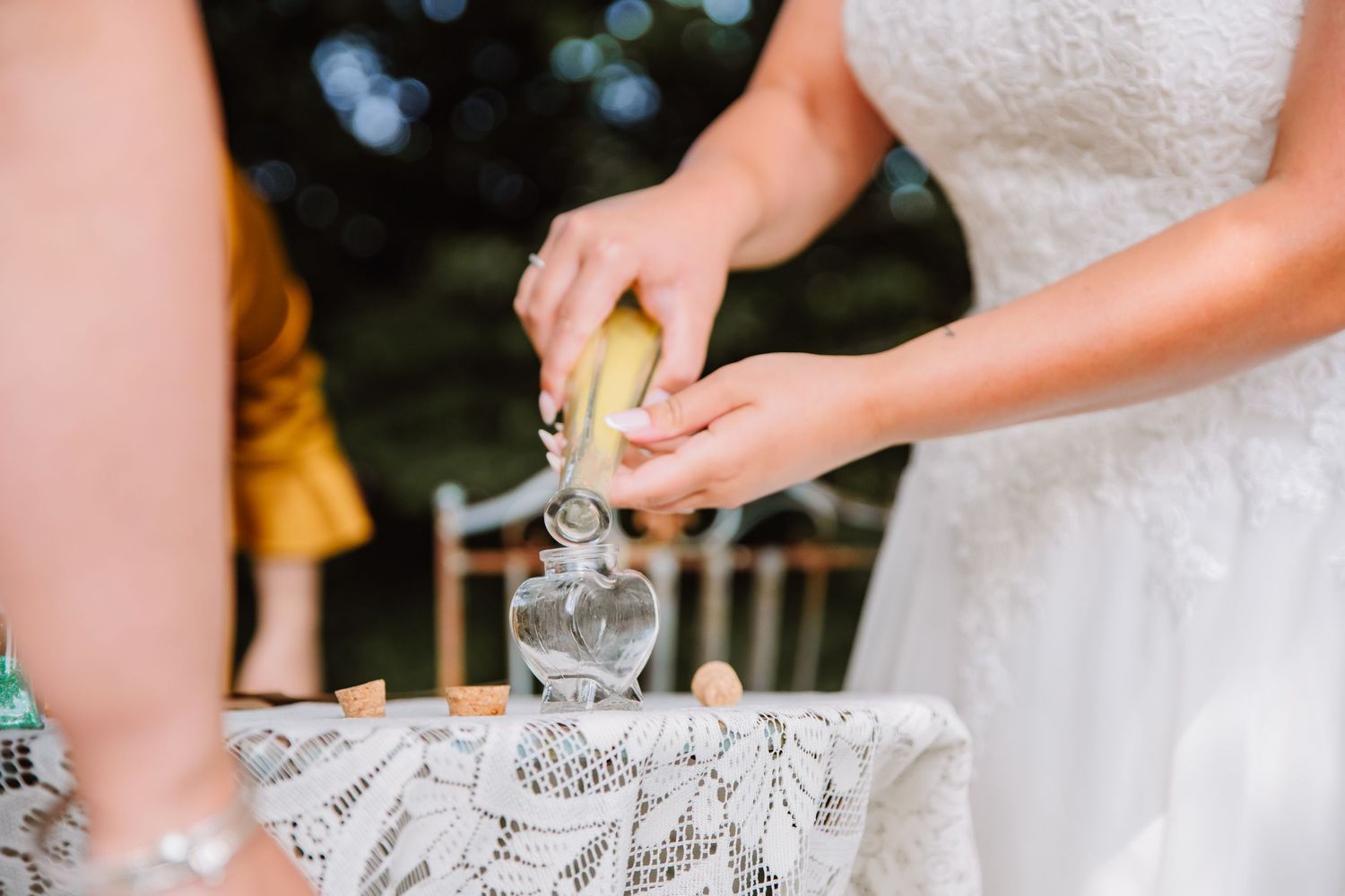 LGBTQ Bride white lace wedding dress pours sand into glasses at an outdoor wedding celebration Dorset wedding at the Gaggle of Geese, Dorset