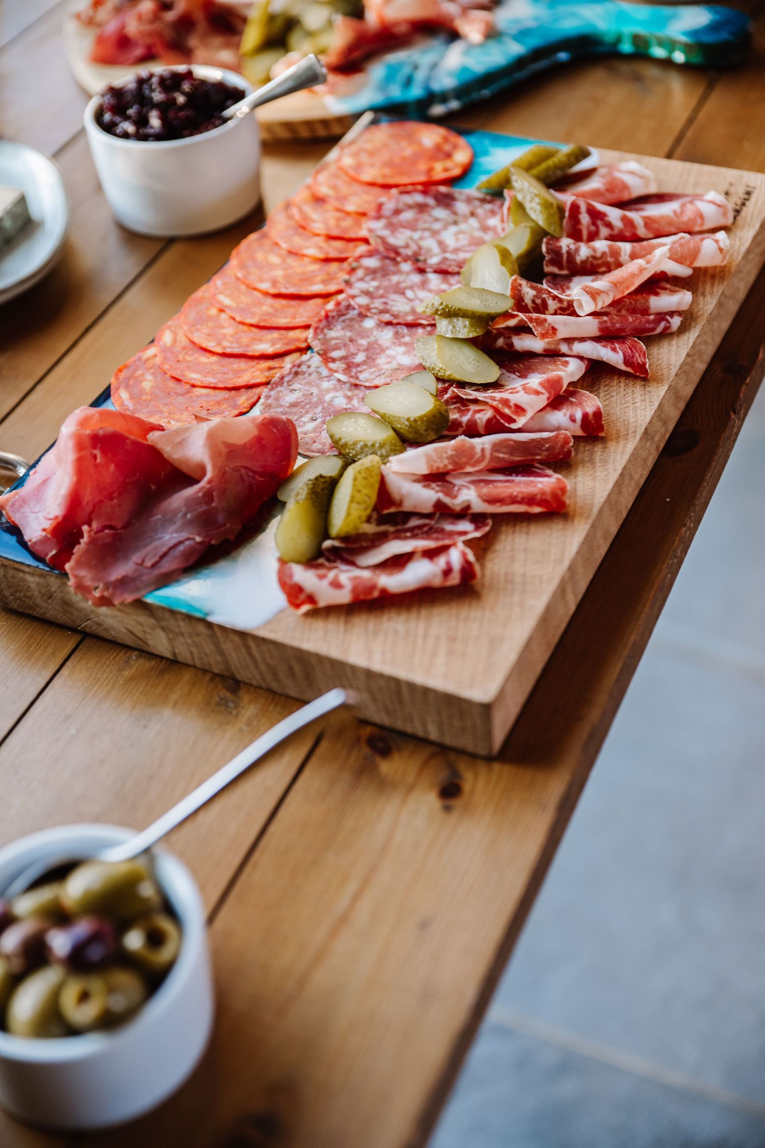 Charcuterie board with salami, prosciutto, pickles, and olives on a wooden table. The Cornish Place, Wood shed wedding