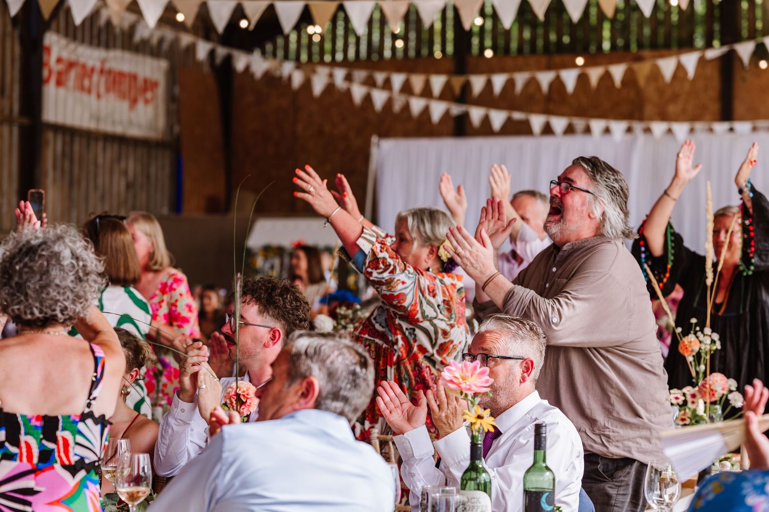 Guests cheer at Dorset Festival barn wedding at Cerne Abbas Brewery. Candid photos from a relaxed Dorset wedding photographer