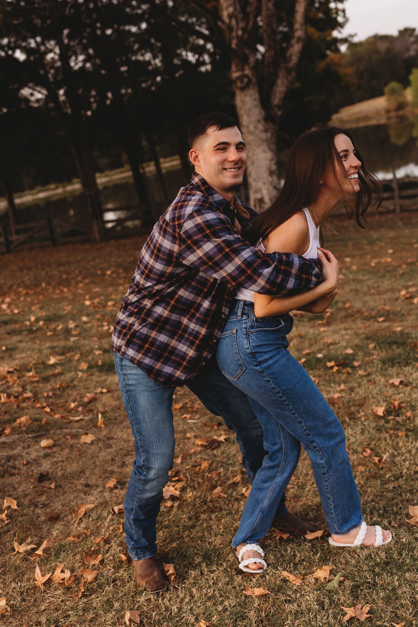 couple guy running up behind her them laughing plaid shirt jeans white tank top