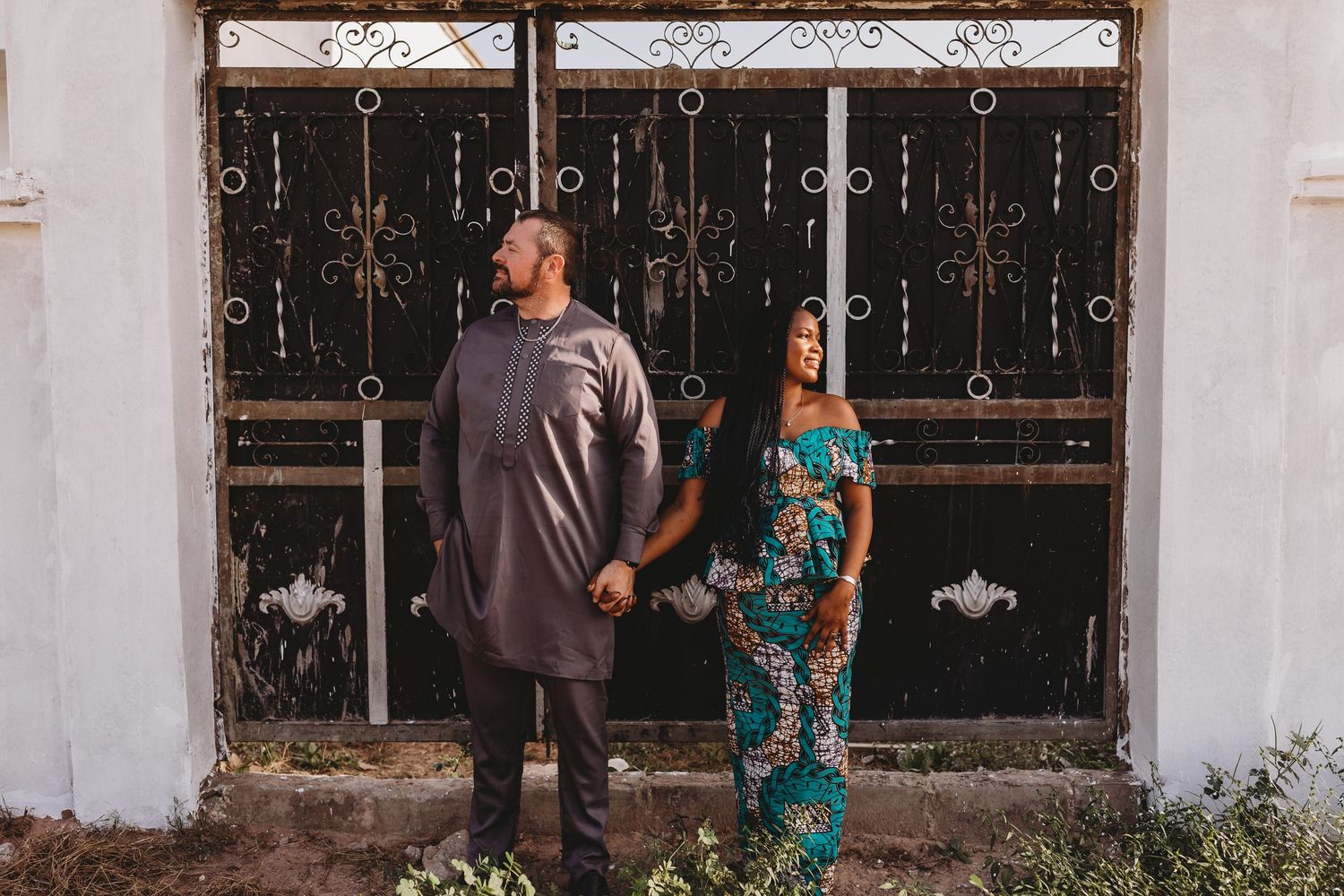 husband and wife Senegal Africa tall black iron ornate gate senegalese wedding attire vibrant blue African pattern