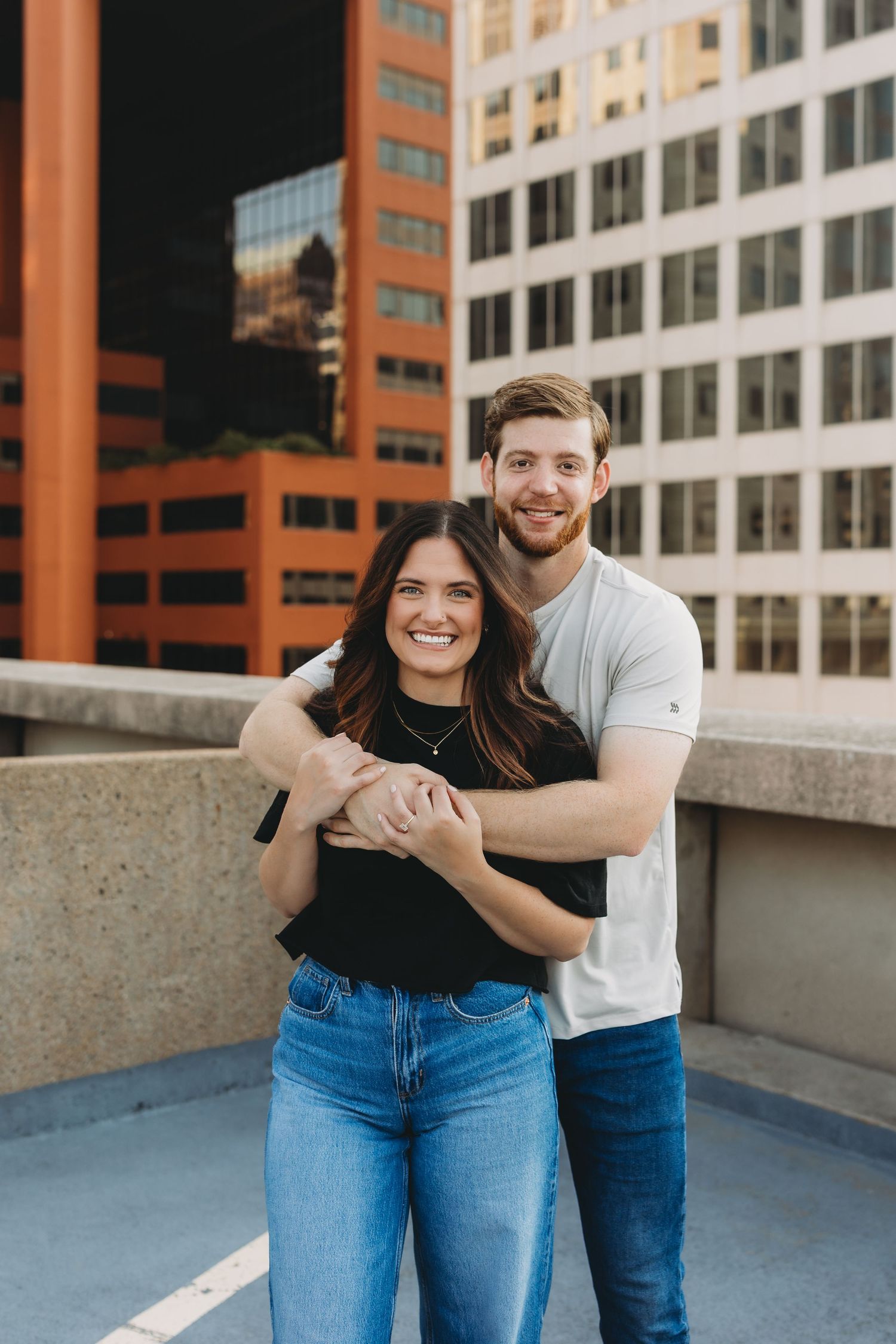 couple embracing on rooftop in st Louis skyscrapers behind them