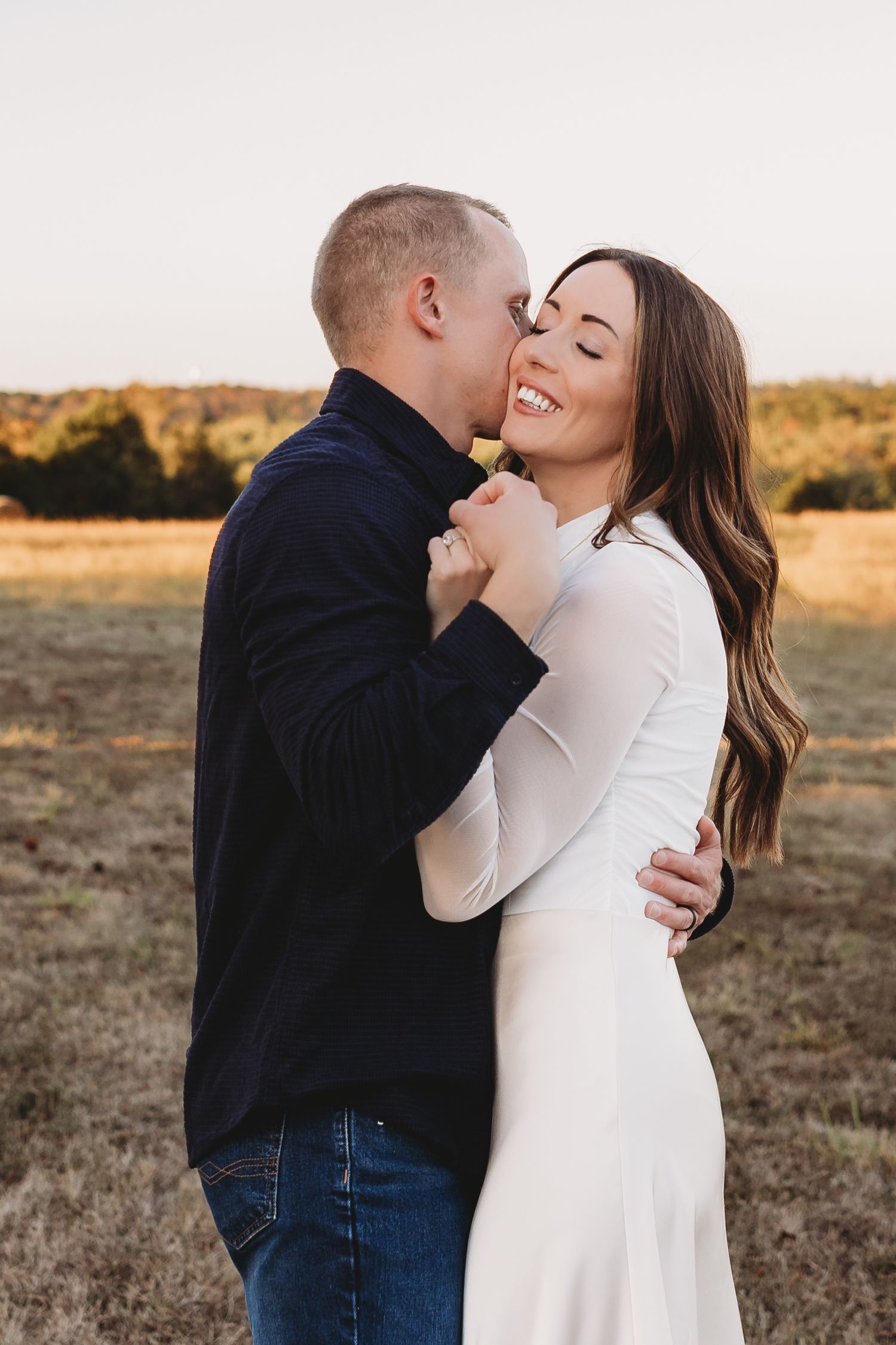 couple white dress black shirt embrace field golden hour