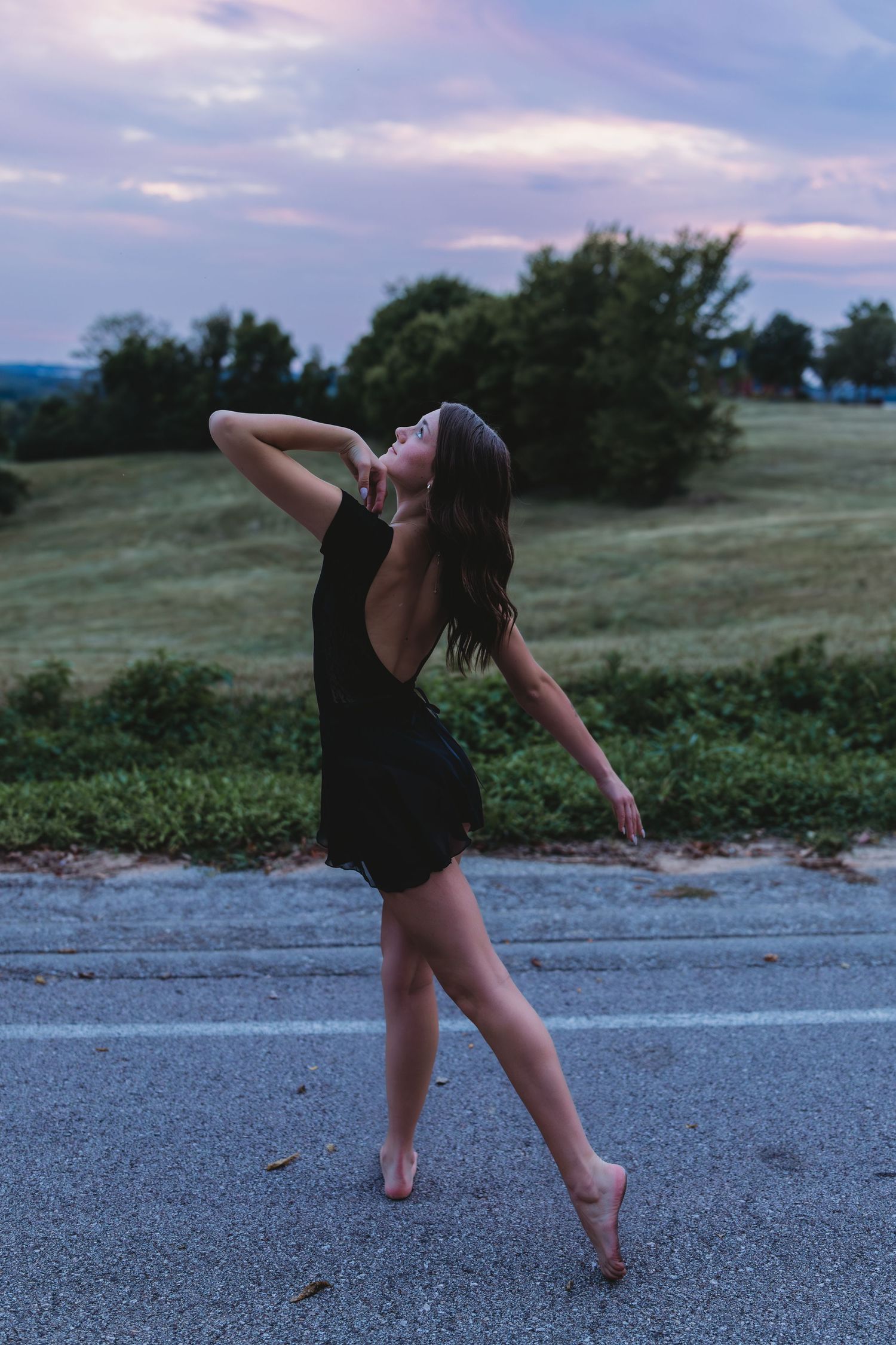 dancer blue hour senior girl black leotard posing with sunset and green field on a road