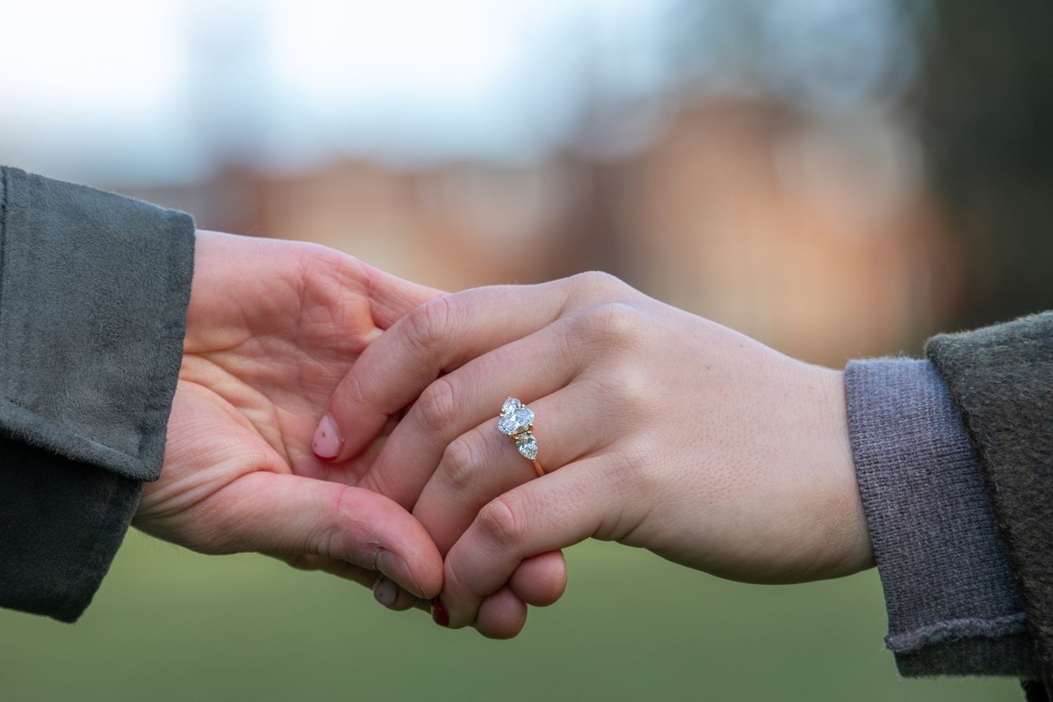 Close-up of couple holding hands showing diamond engagement ring during romantic proposal moment.