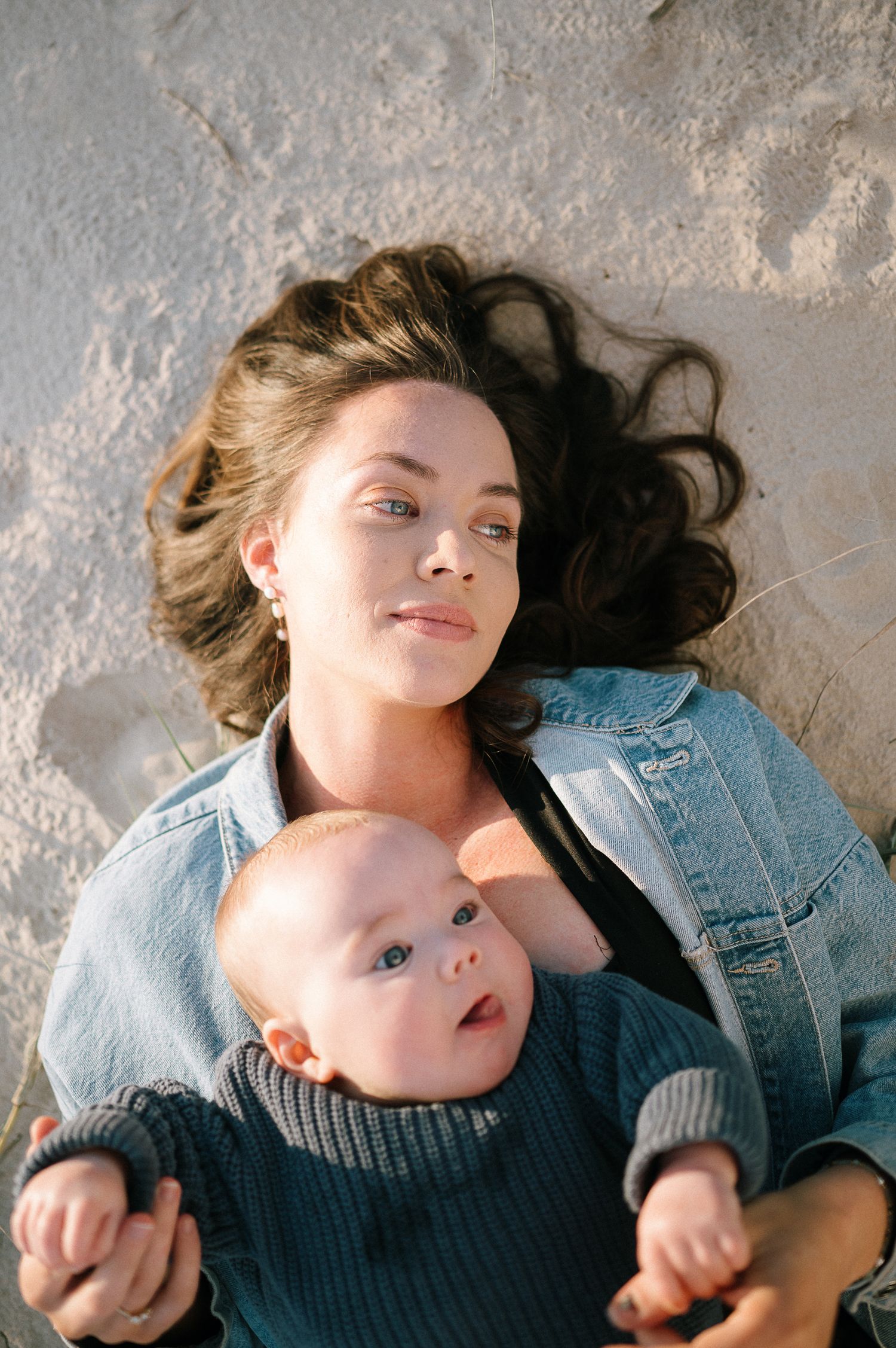 Two people lying together on textured surface in casual attire.