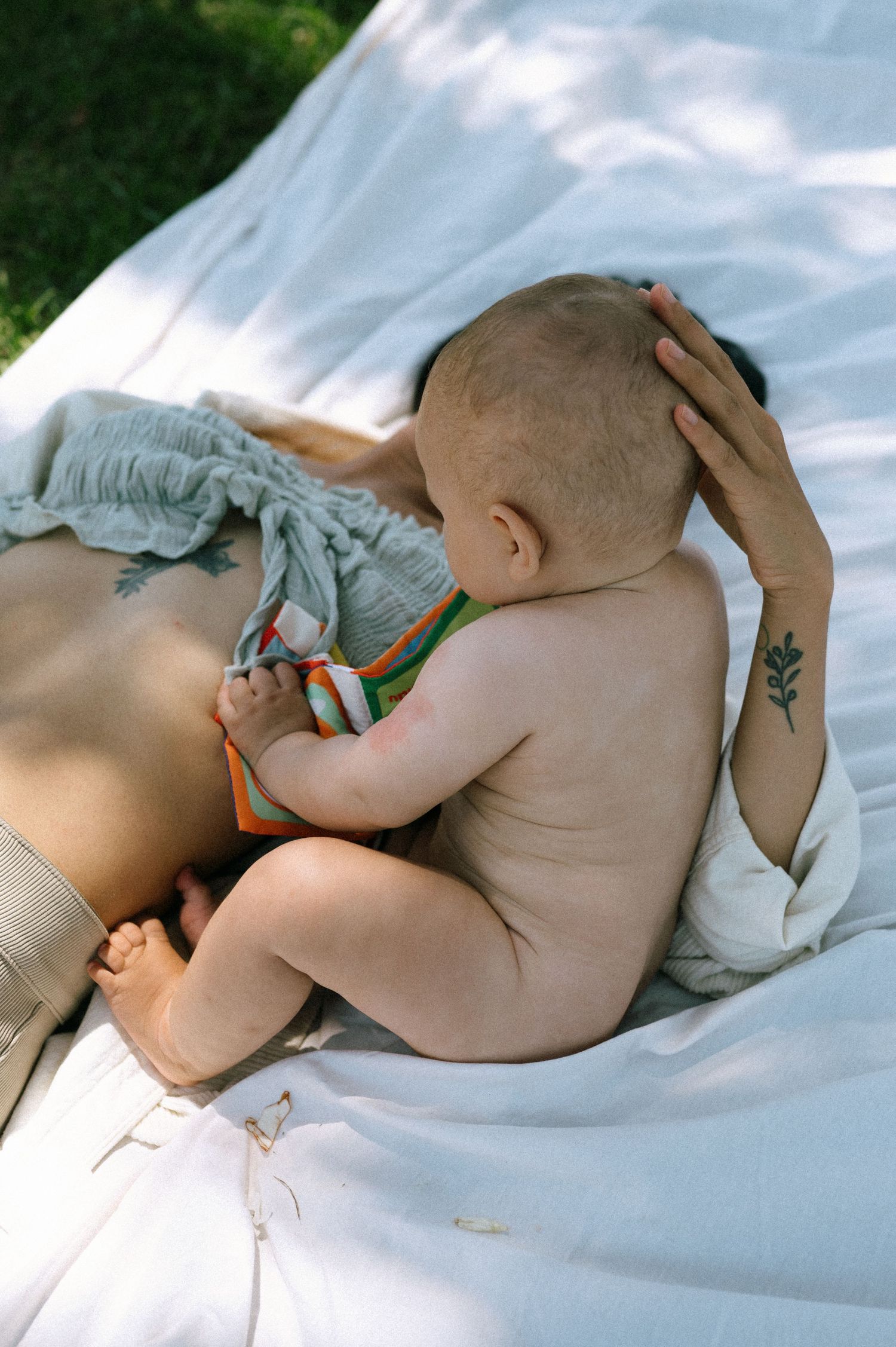Peaceful newborn rests on white bedding in natural sunlight.