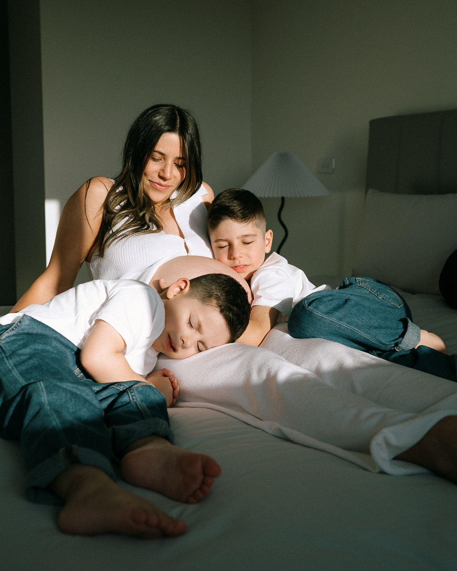 Tender moment of rest and connection in soft bedroom lighting.