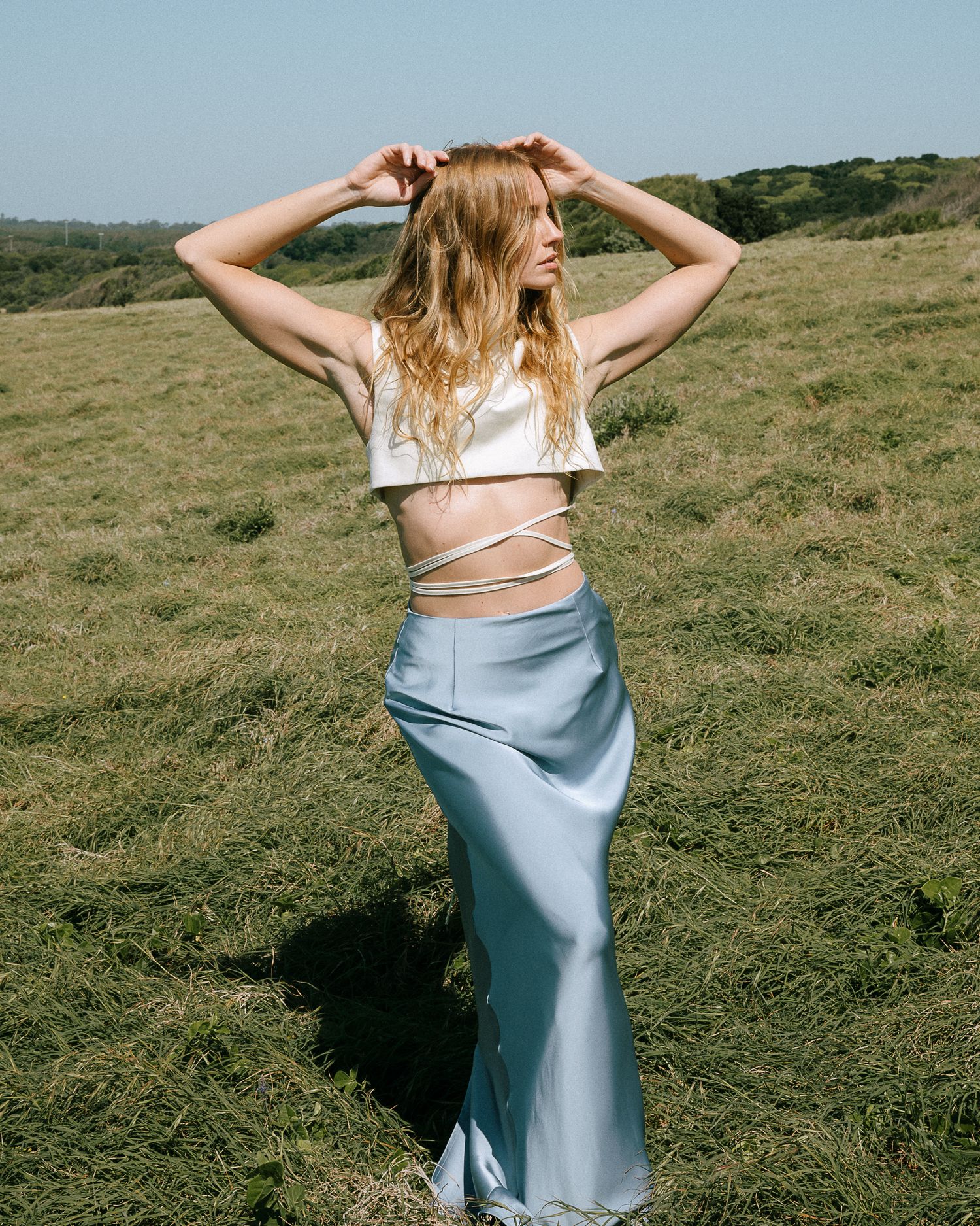 Fashion series in meadow with flowing silk dress and natural lighting.