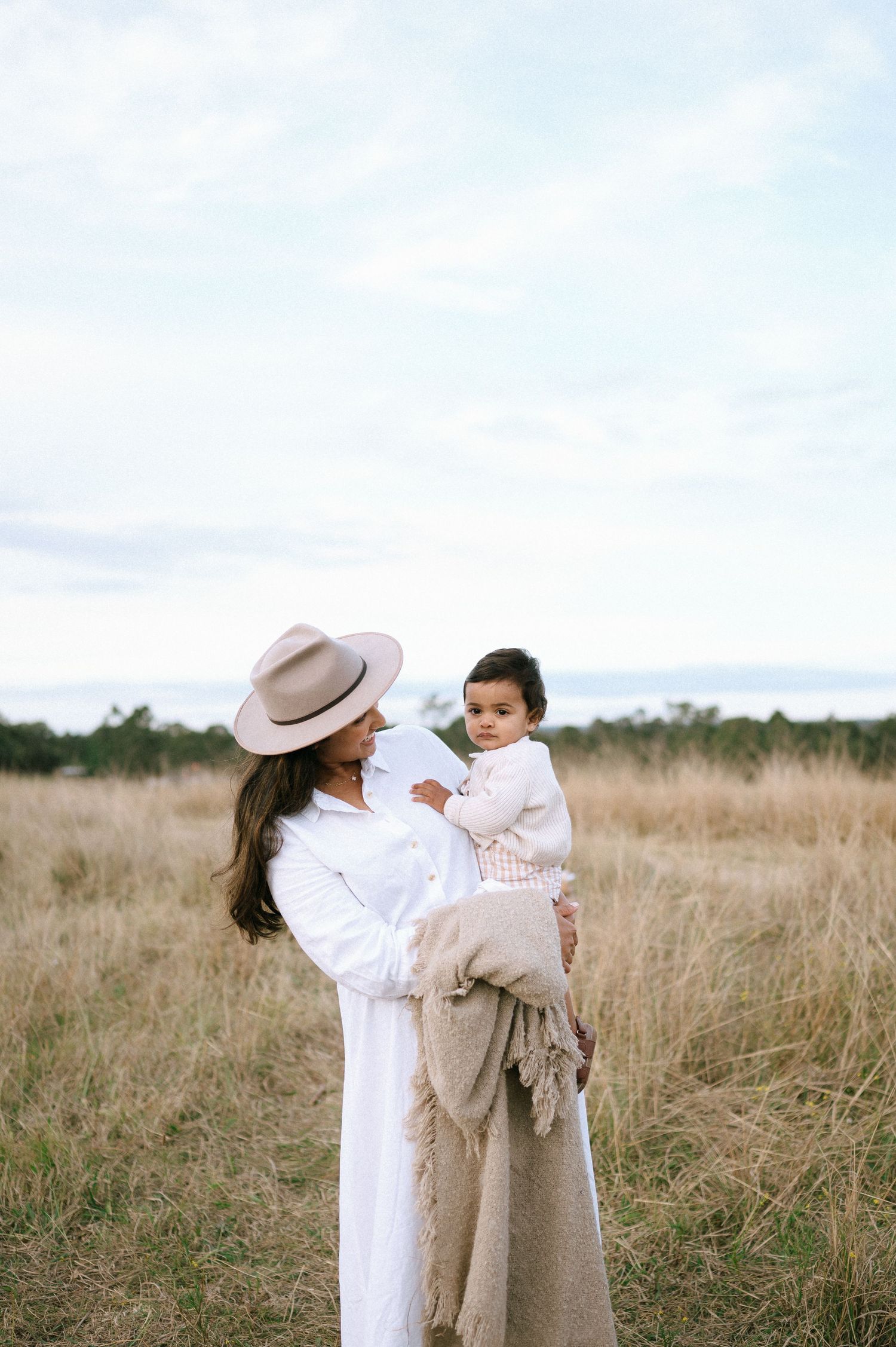 Two people in white outfits playing together in tall grass field.