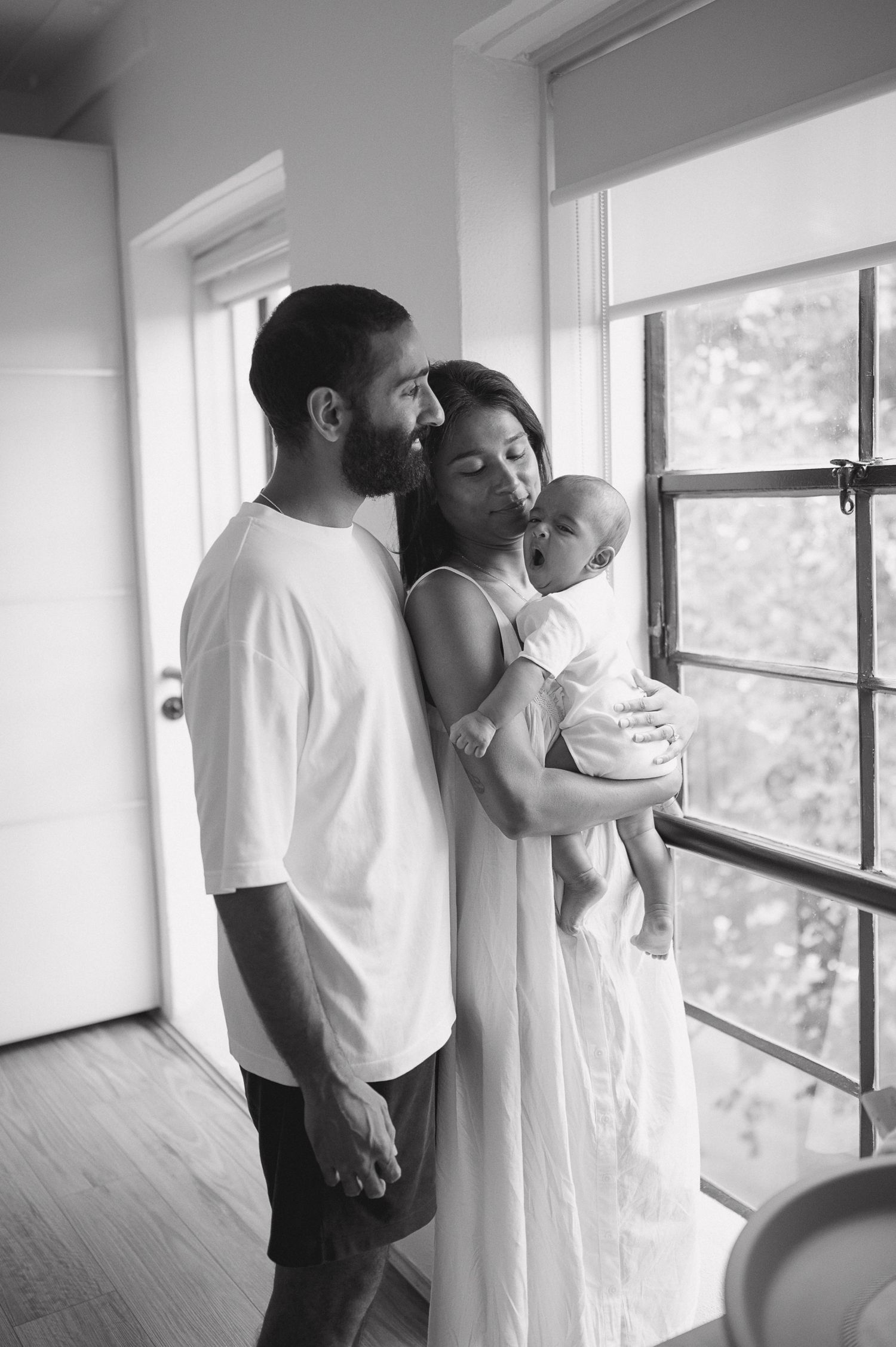 Black and white intimate couple photoshoot showing tender moments by a window.