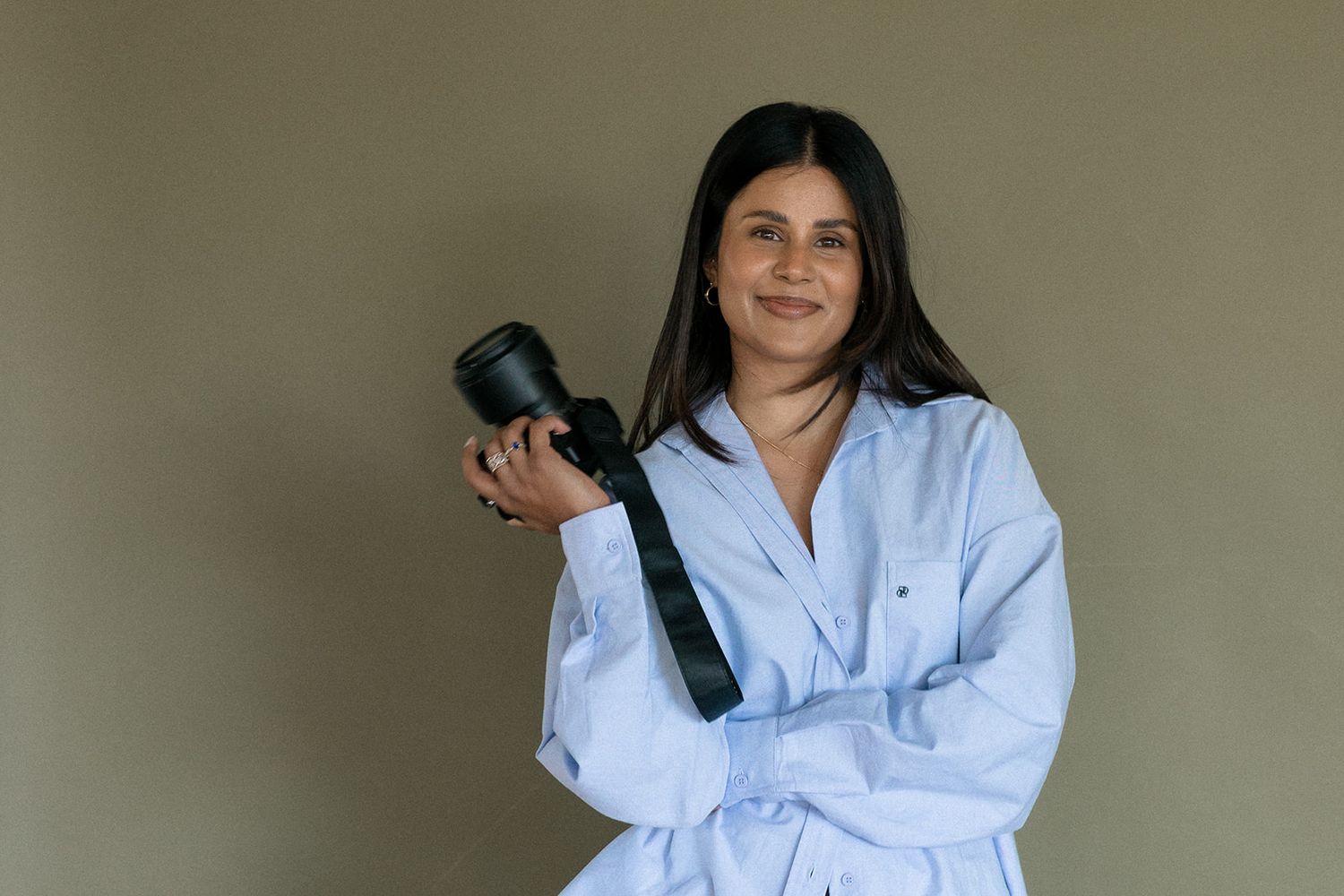 Photographer wearing light blue button-down shirt in casual indoor portrait series.