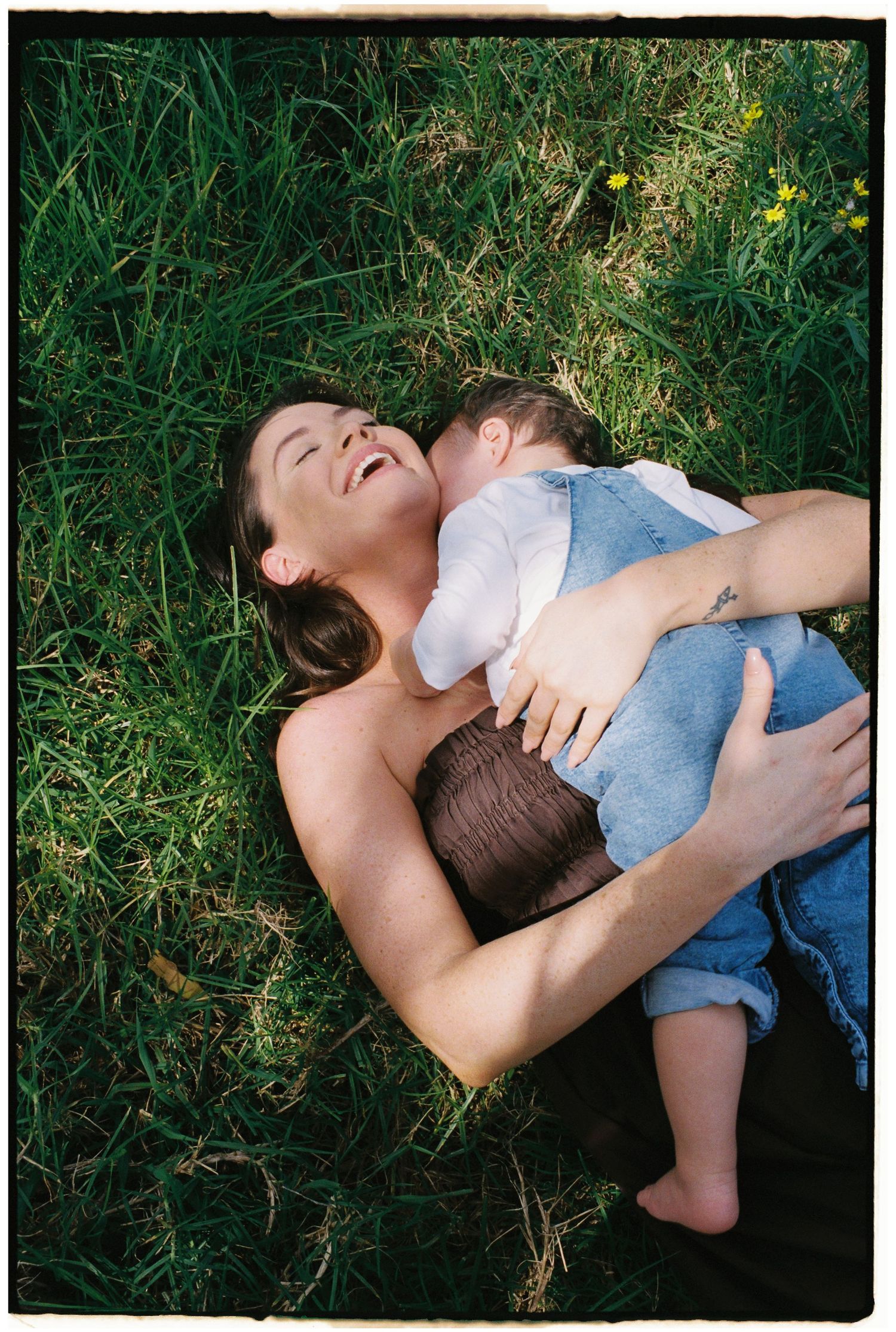 A tender embrace captured in lush green grass with yellow wildflowers.