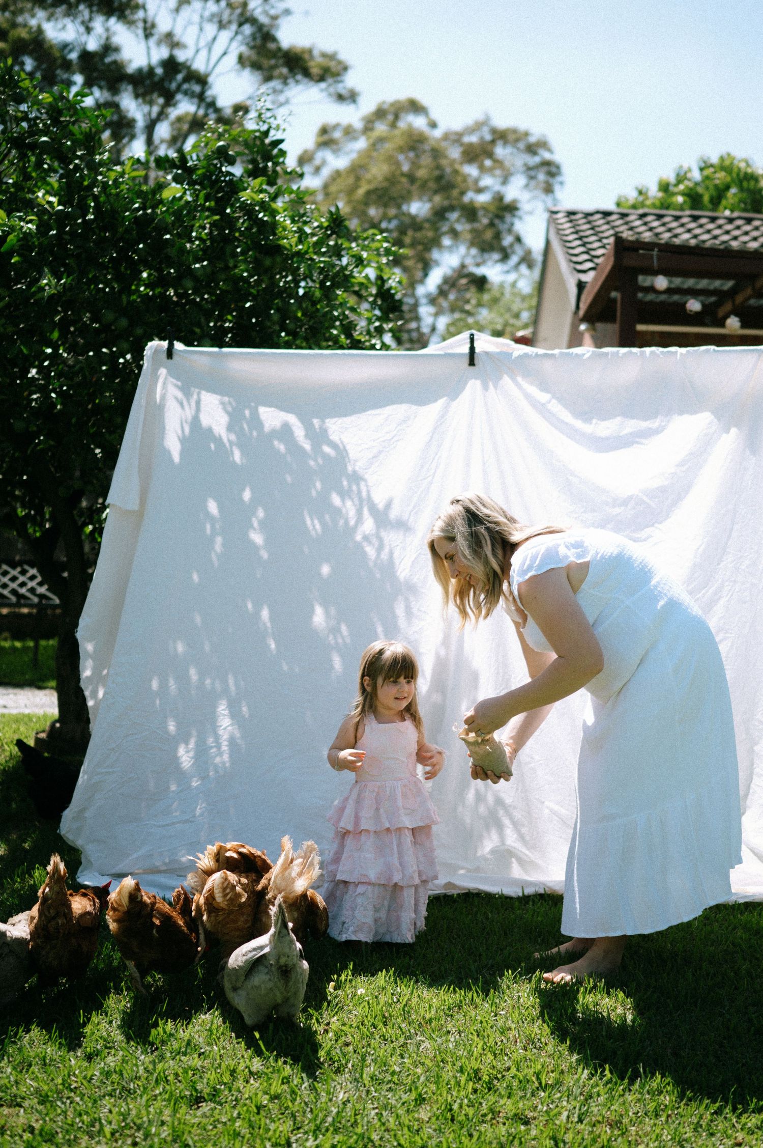Playful scene of figures ducking behind white laundry hanging in sunny garden.