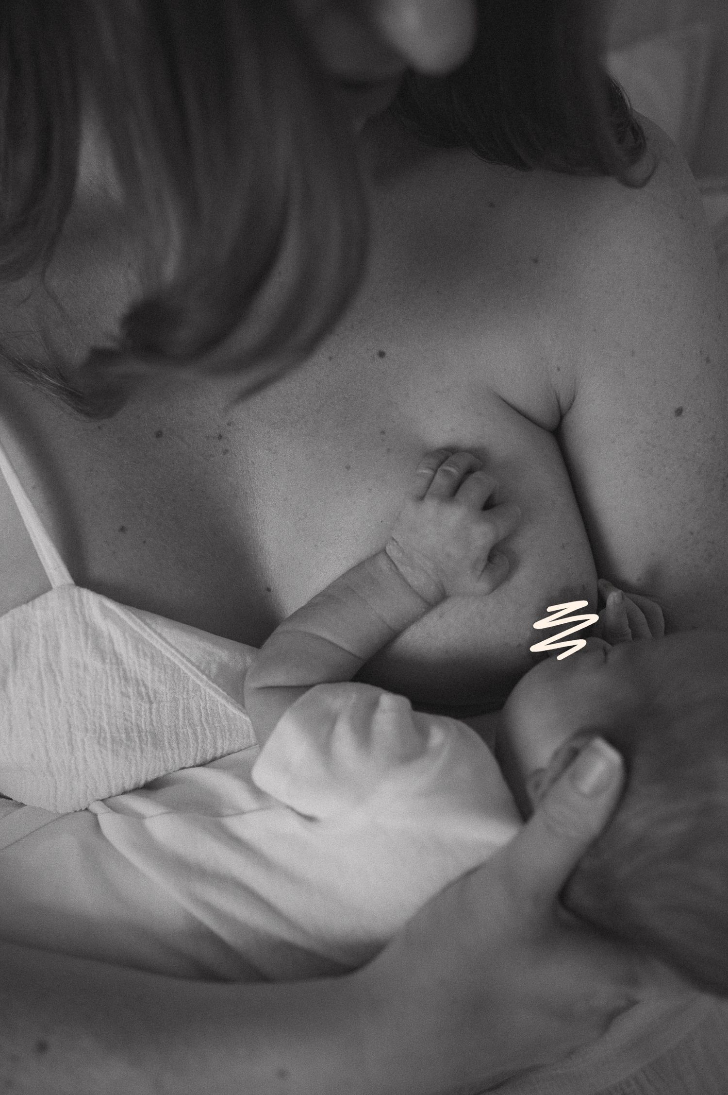 Black and white photo of a mother breastfeeding her newborn baby, a tender and intimate moment of bonding.