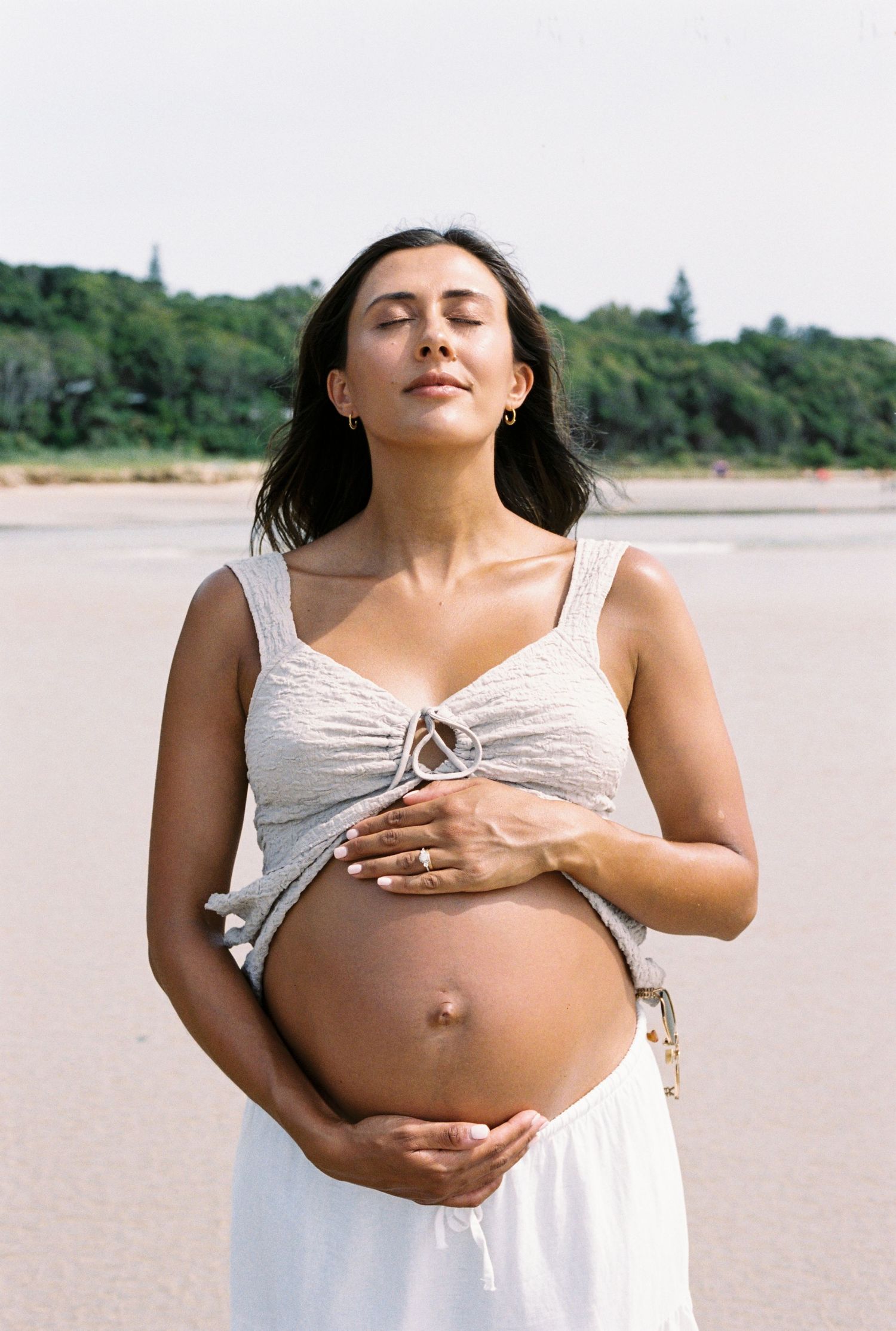Pregnancy progression photos on beach in white dress.