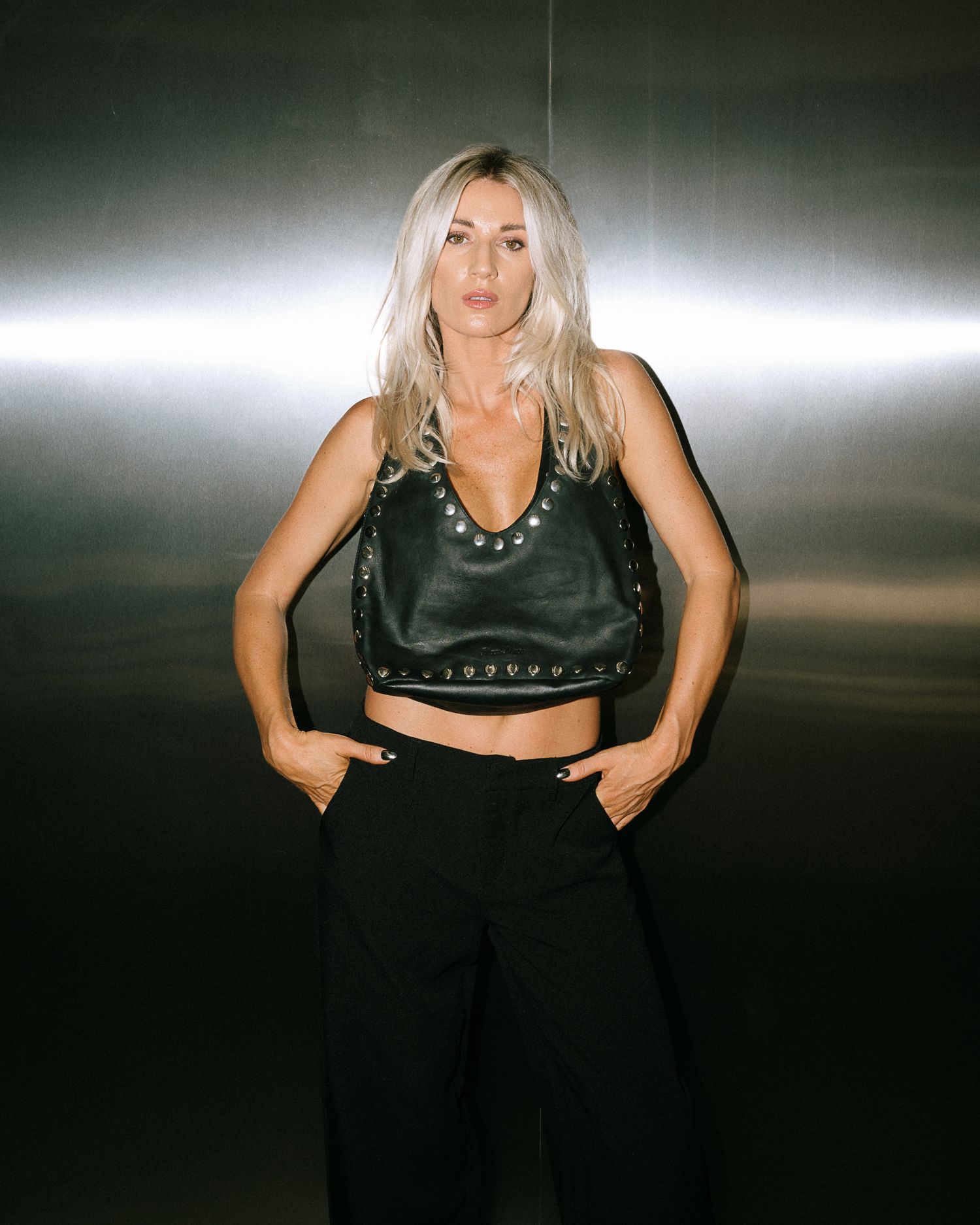 Fashion shoot of person in dark clothing against dramatic studio lighting.