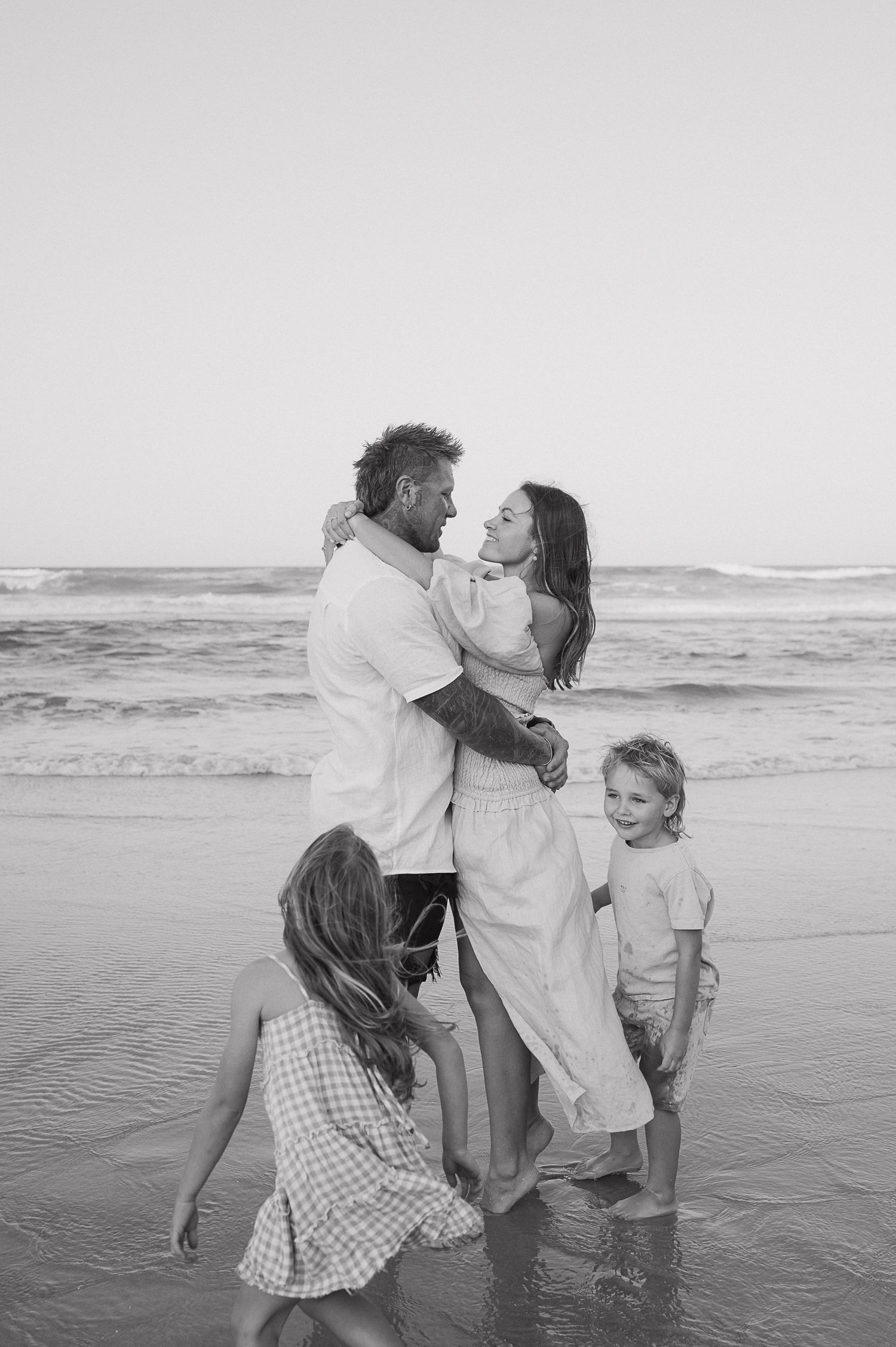 Family enjoying a playful moment together at the beach during sunset.
