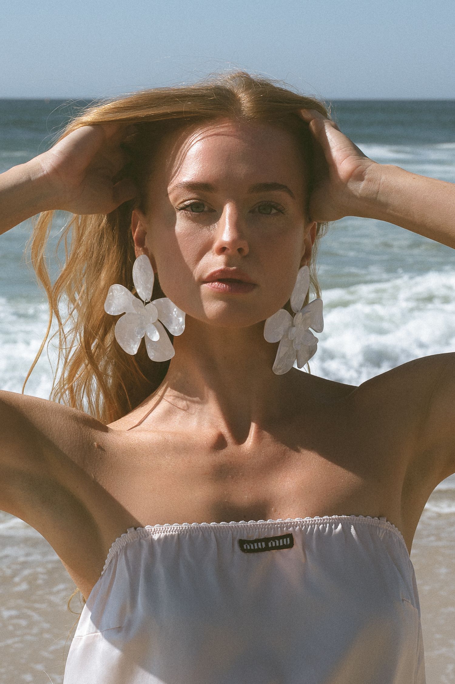 Dreamy seaside photoshoot featuring white butterflies and natural sunlight.