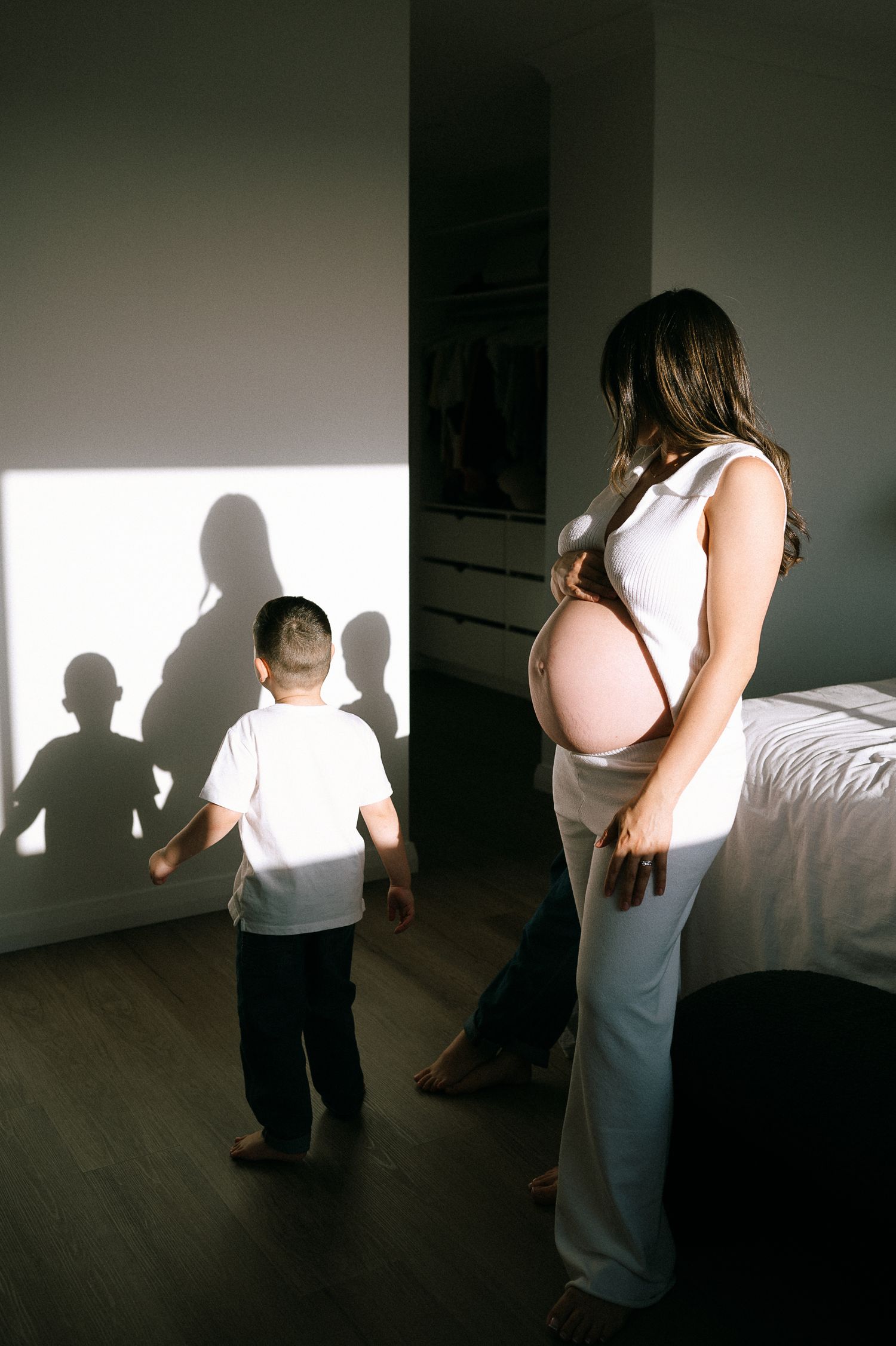 Shadows and light play across a room as figures move in a minimalist space.